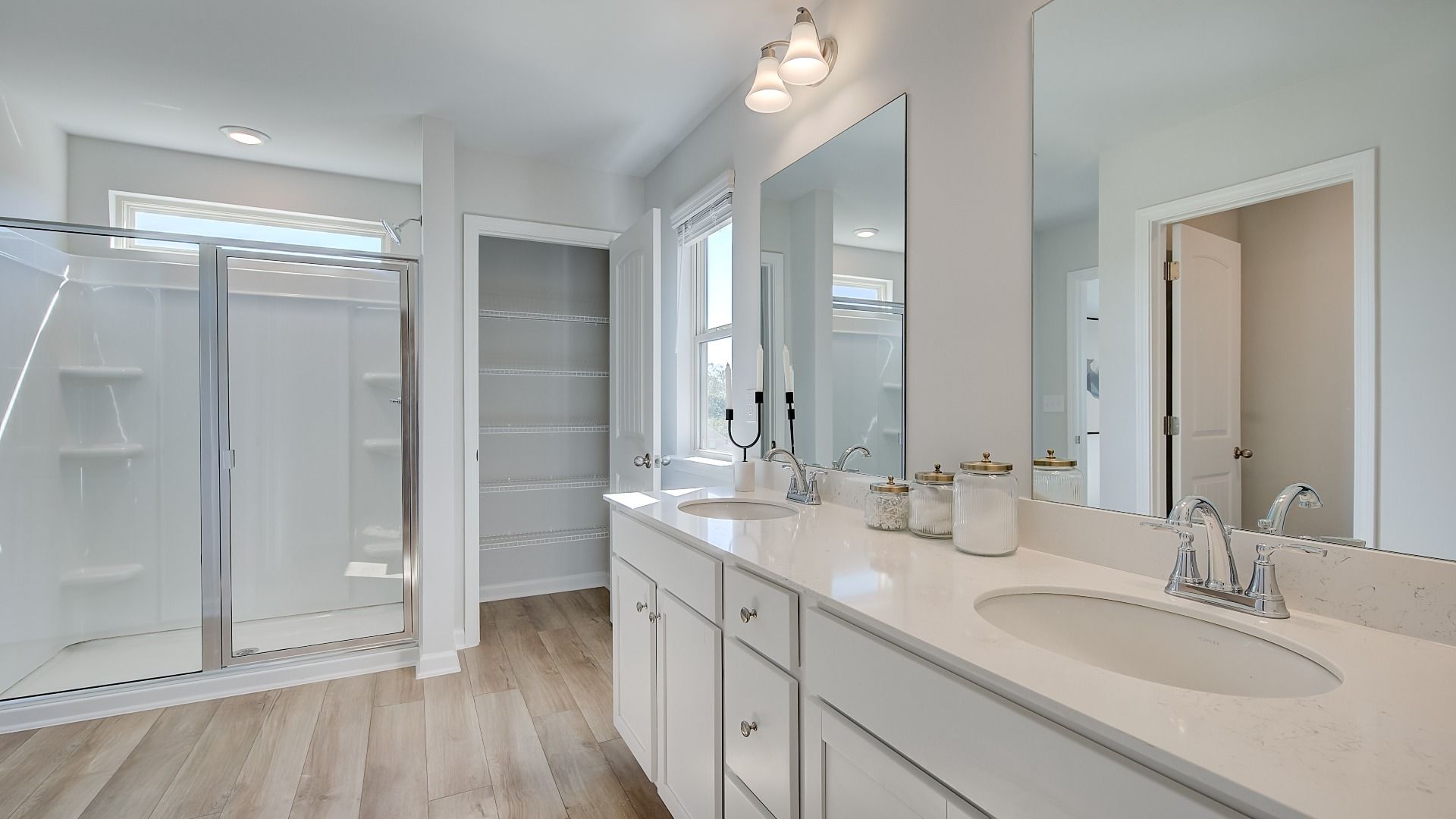 Primary bathroom with dual vanities, large walk-in shower, and modern quartz countertops in new construction home.