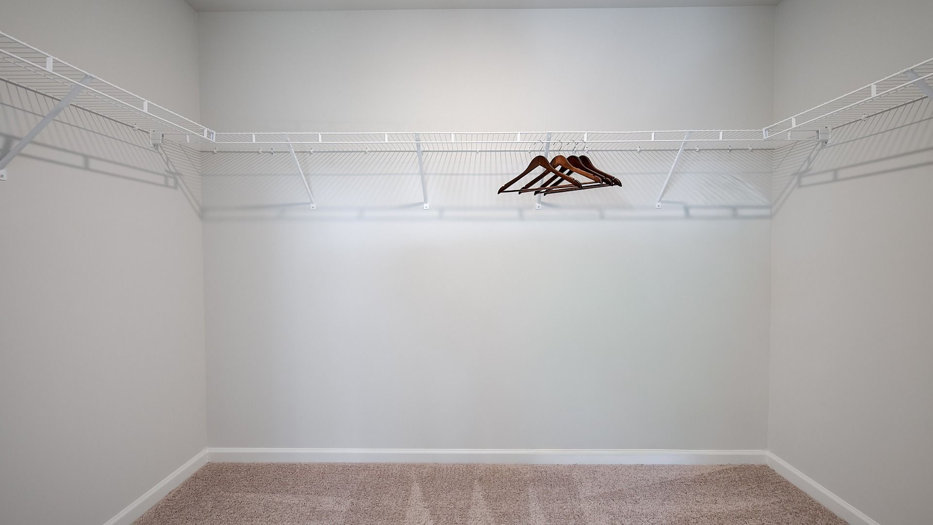 Generous walk-in closet with built-in shelves, hanging rods, and storage space in new construction home.