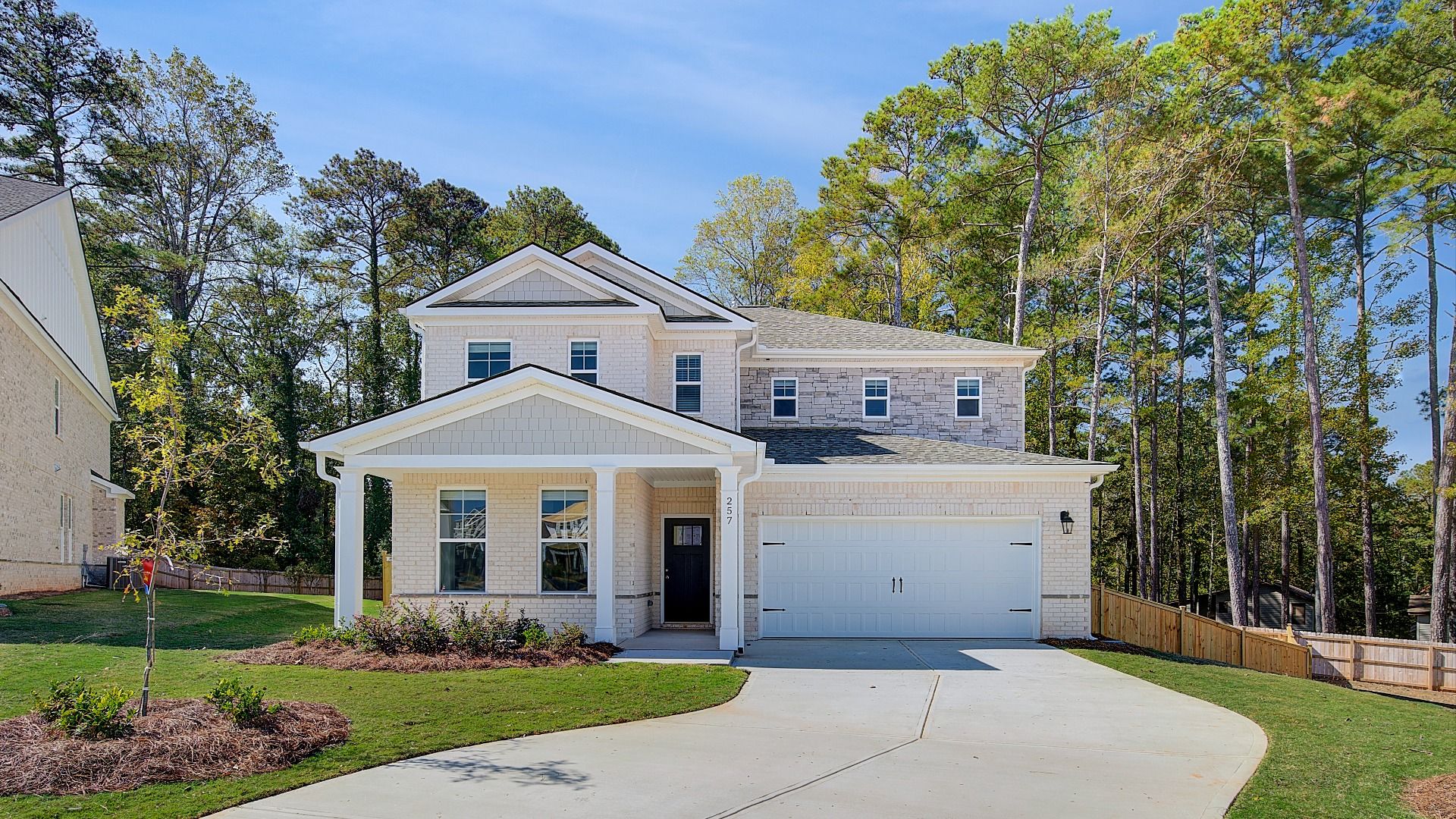 Wynwood two-story light brick home with stone accent and front-entry two-car garage at Burchwood in Stockbridge, GA.