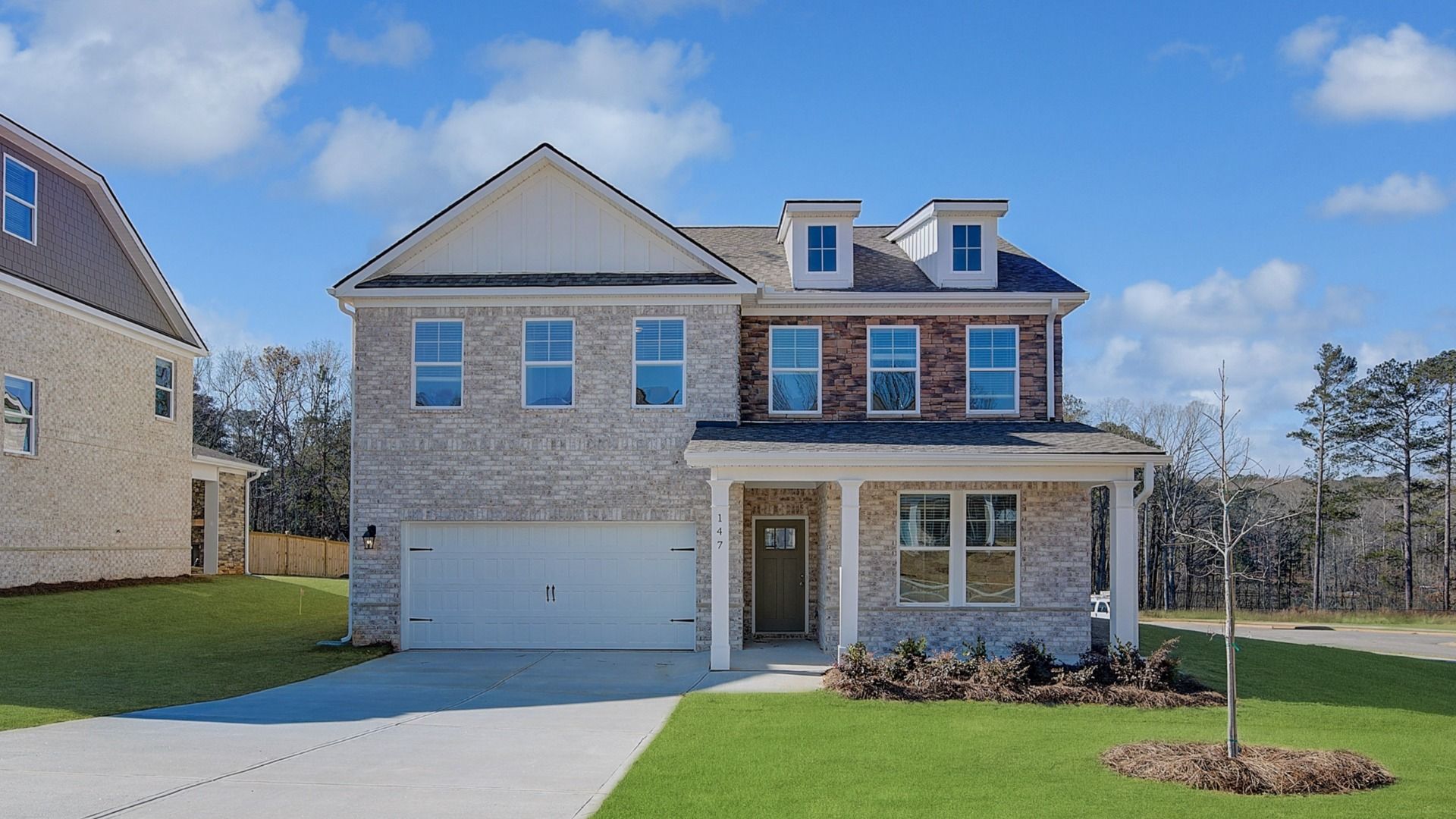 Wynwood two-story brick home with stone accent and front-entry two-car garage at Burchwood in Stockbridge, GA.