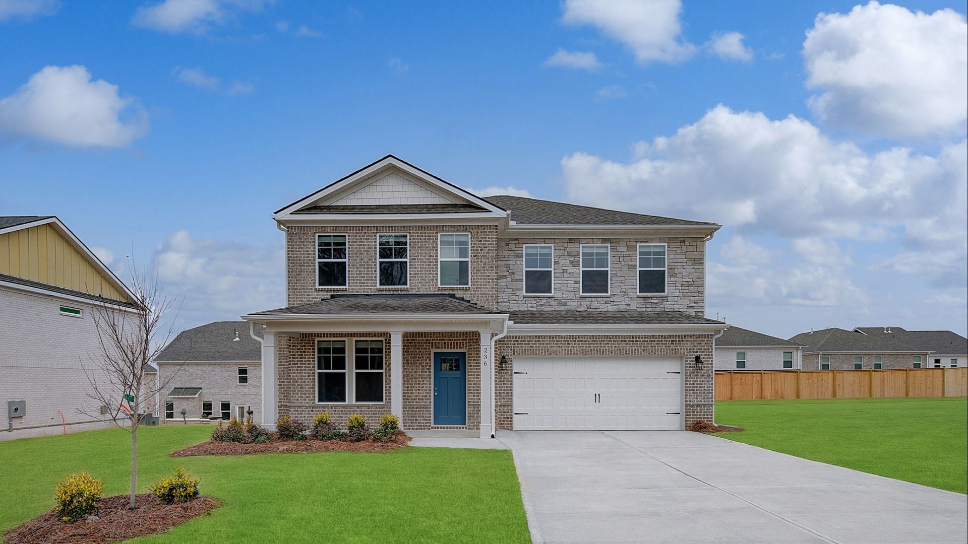 Two-story Ridgewood home exterior with stone and brick, spacious front yard, and front-entry garage in Stockbridge, GA.