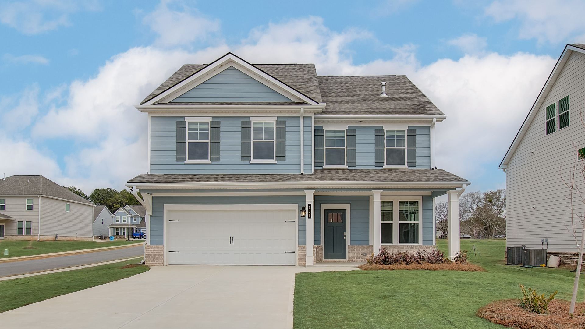 Two-story Devon model home exterior featuring manicured landscape and front-entry garage at Cooper Park in McDonough, GA.
