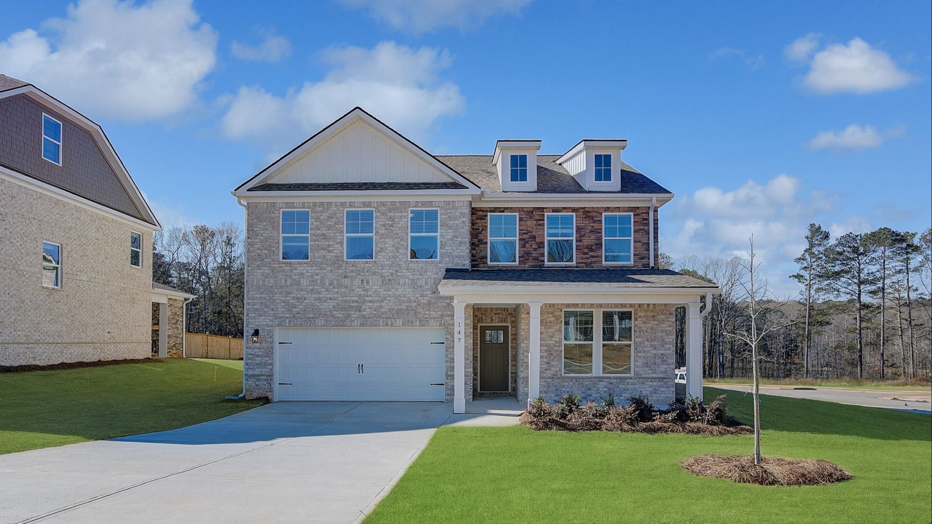 Wynwood two-story brick exterior with stone accents, two-car garage, and front yard space at Burchwood in Stockbridge, GA.