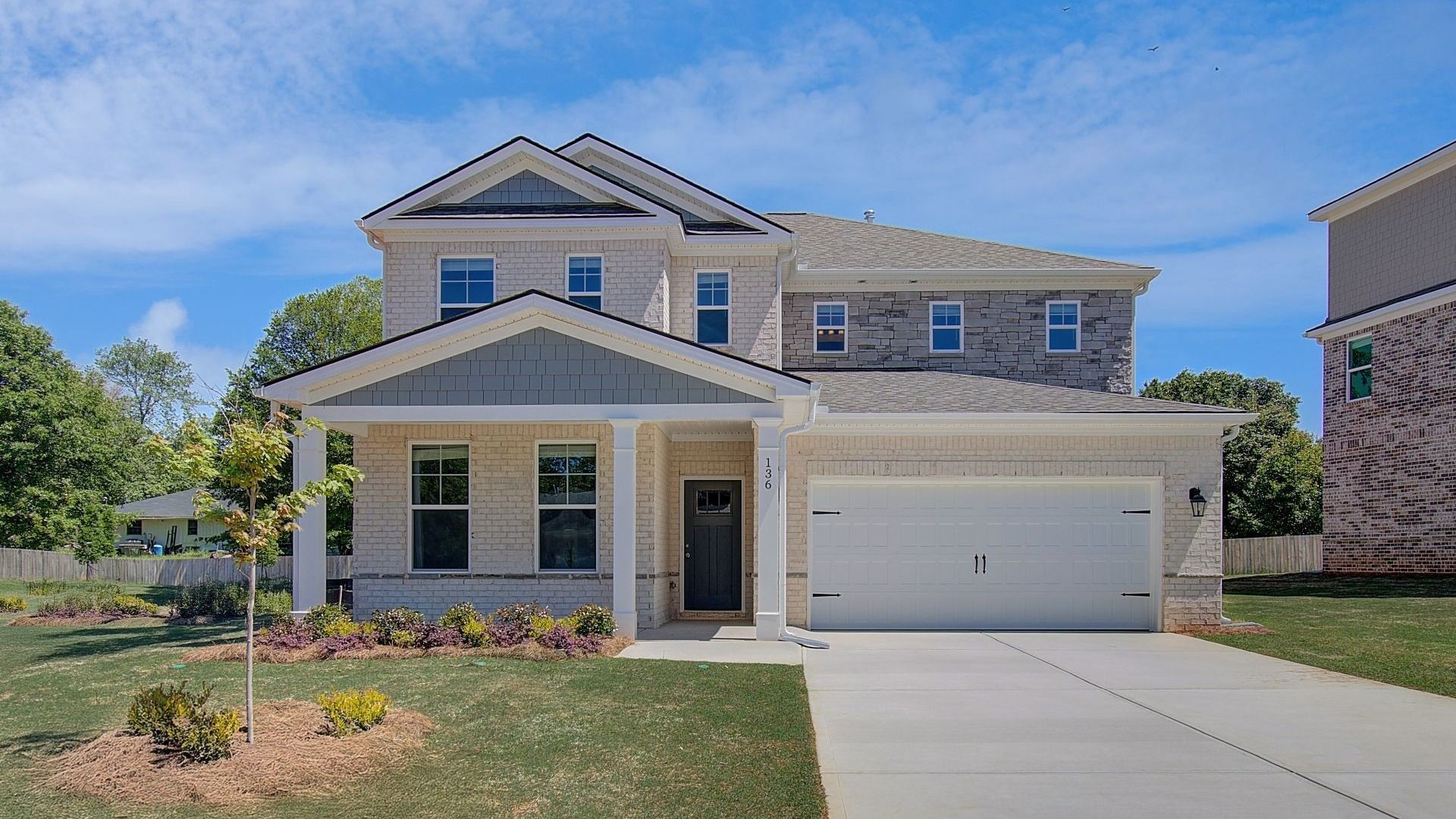Wynwood two-story exterior with brick, stone, and siding accents, abundant windows, and a two-car garage in Stockbridge, GA.