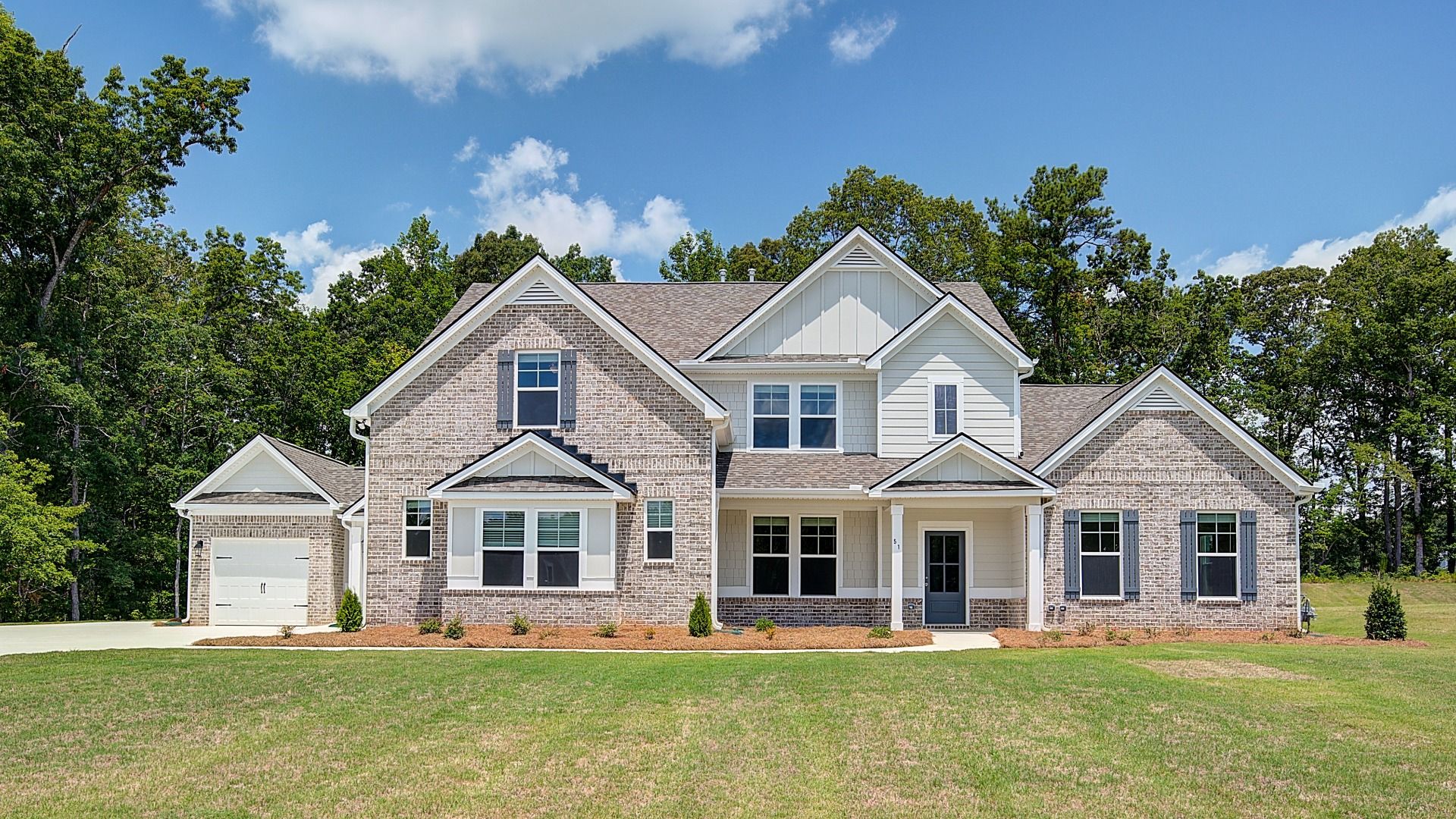 Two-story Margaret single-family home exterior with brick feature and three-car garage at Saddleridge in Senoia, GA.