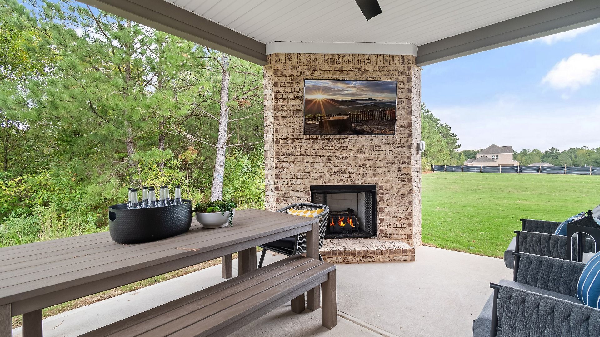 Covered gameday porch with brick gas fireplace and seamless flow into spacious back yard  at Trinity Park in McDonough, GA.