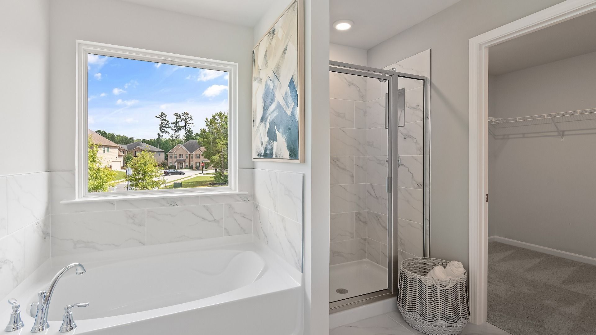 Primary bath with tile-finished soaking tub and walk-in shower, and walk-in closet at Westminster in Covington, GA.
