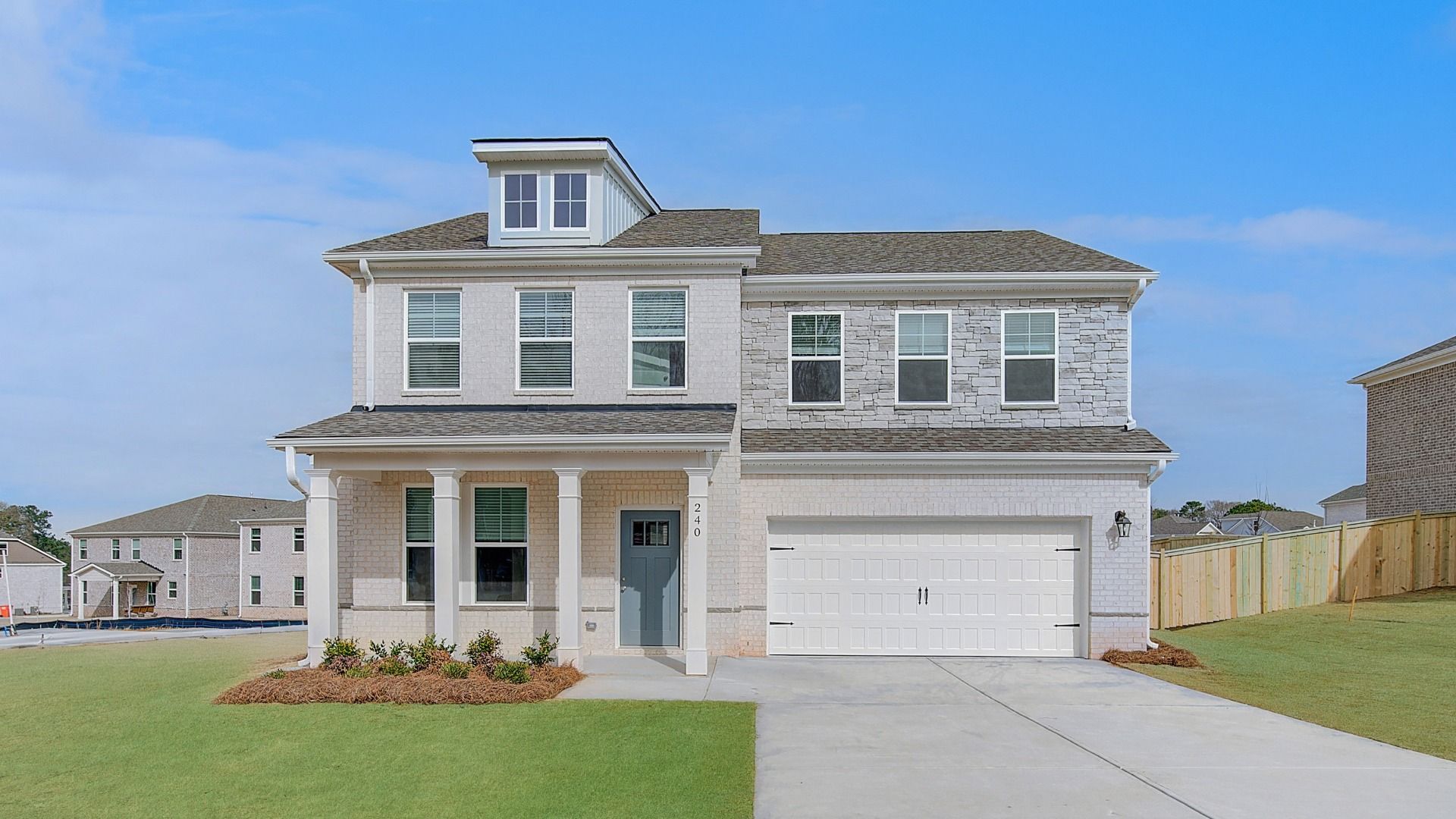 Ridgewood two-story home with brick-dominant exterior, stone accent, and two-car front-entry garage at Burchwood.