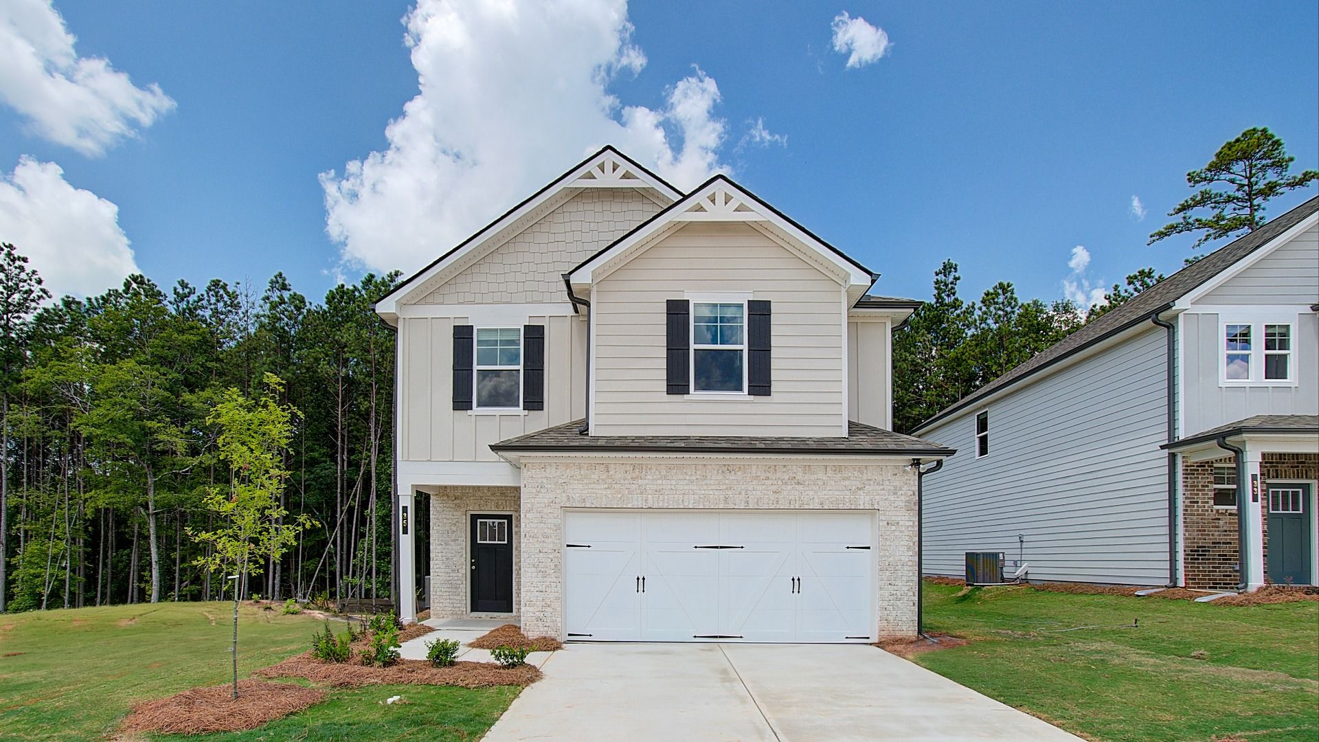 Two-story home in Conyers, GA with gray siding, brick facade accents, prominent windows, and an attached two-car garage.
