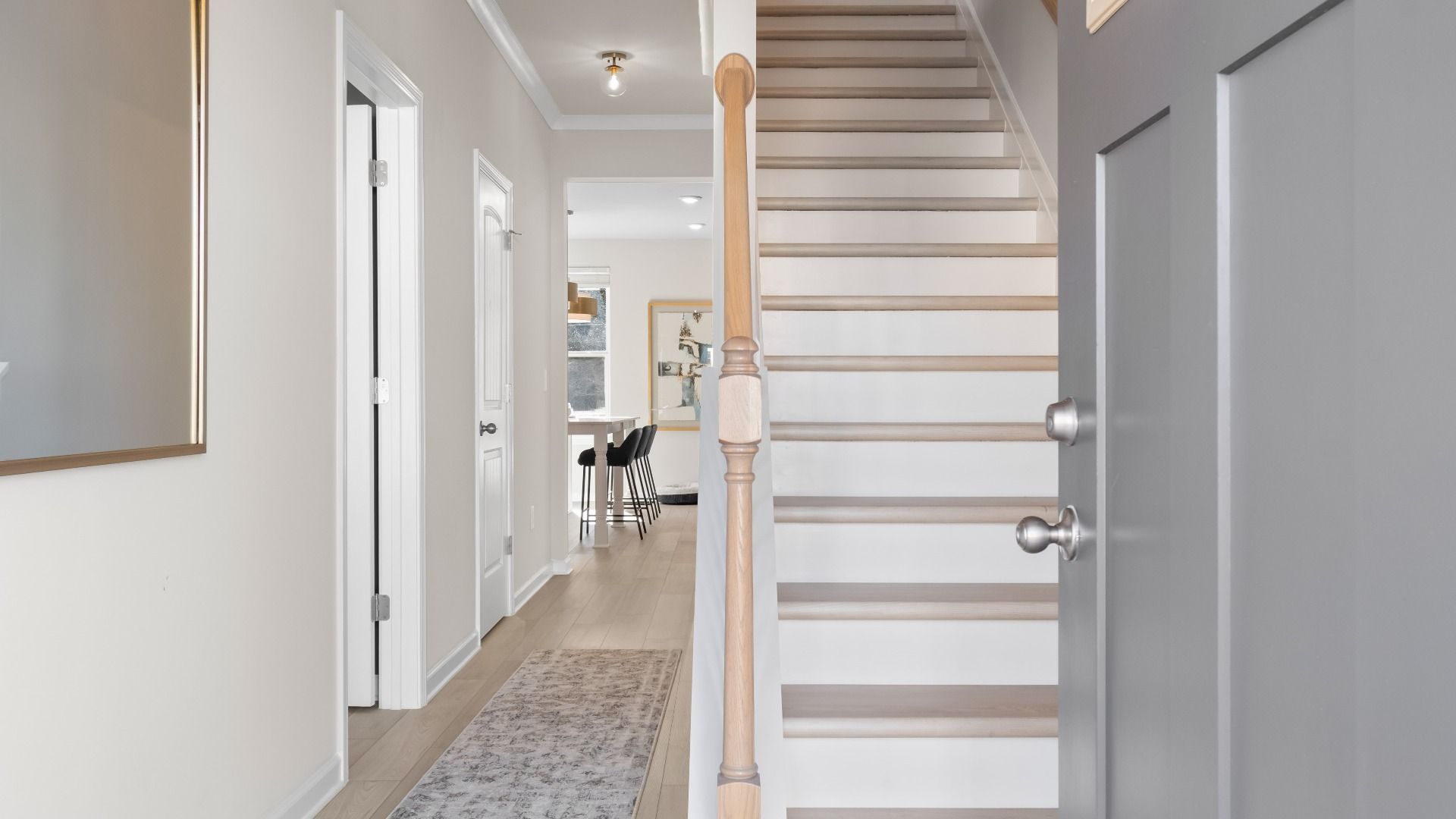 Ridgewood entry with neutral gray front door, open hallway and staircase at Abbotts Crossing in Conyers, GA.