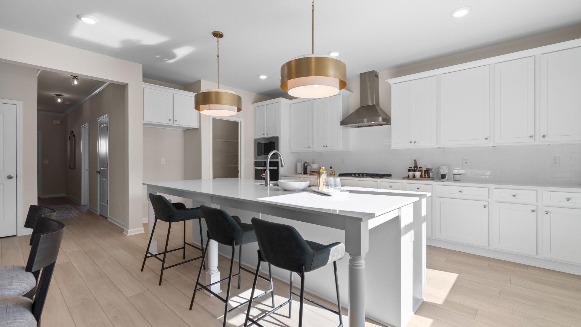 Bright modern kitchen with island seating, white tile backsplash and abundant cabinetry at Abbotts Crossing in Conyers, GA.
