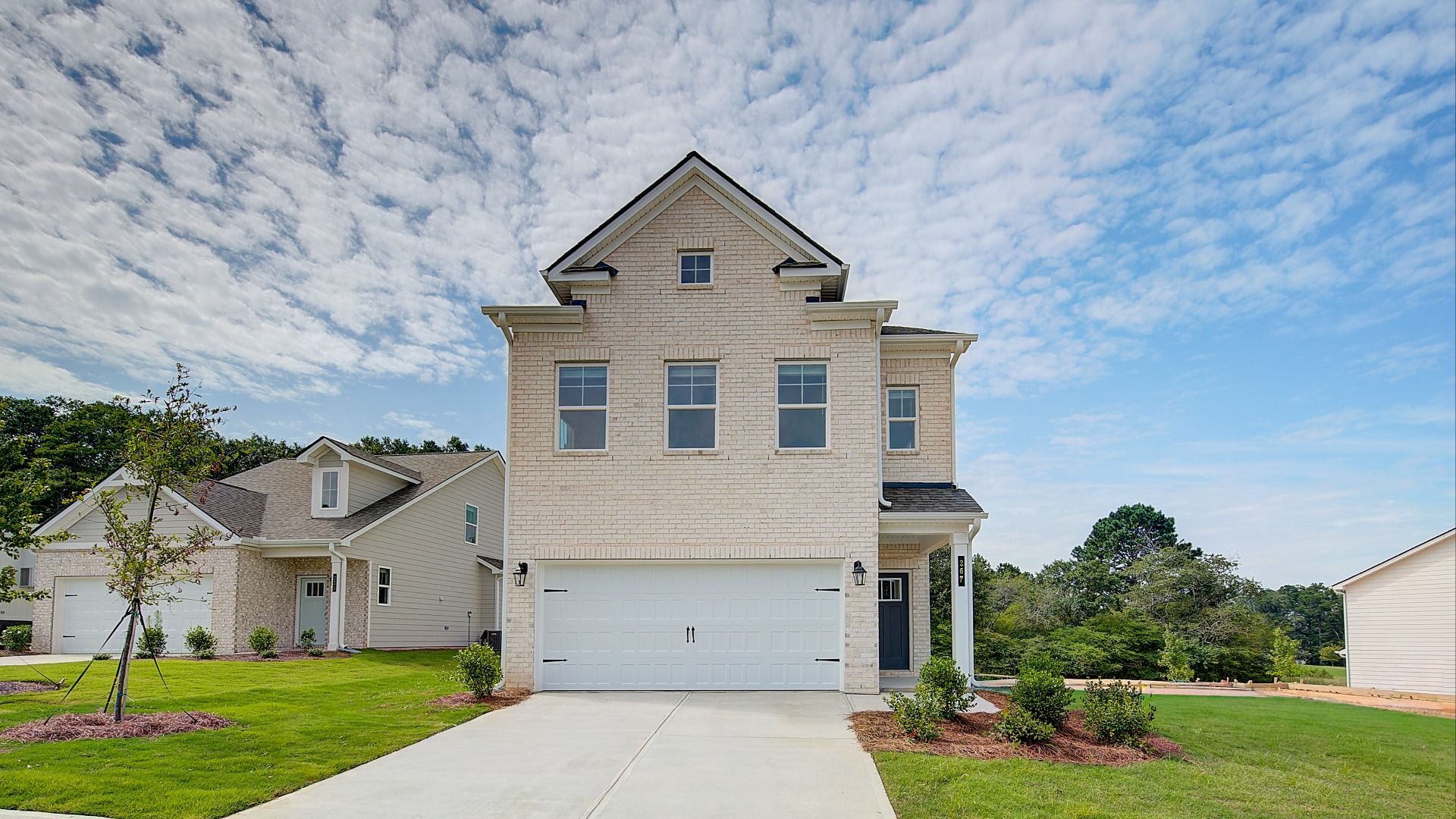 Two-story new brick home with covered entry, white trim accents, and spacious two-car garage in Conyers GA.