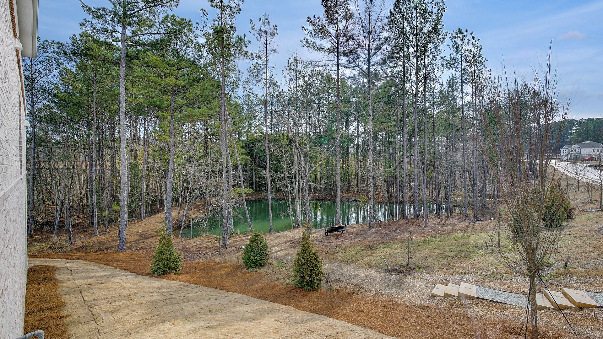 Community pond with outdoor seating area accessible via walking trails in Hamilton Lakes in Lawrenceville, GA.