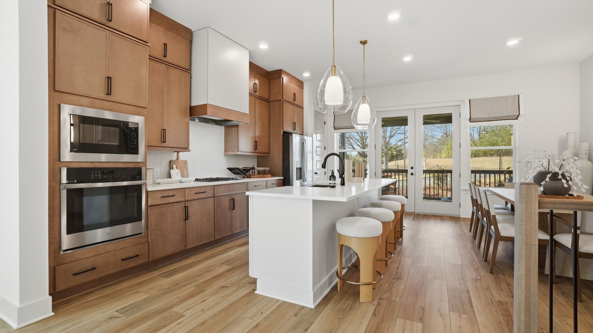 Modern open-concept kitchen with LVP flooring, expansive island, and pendant lighting in the Seaton at Barrett Pointe.