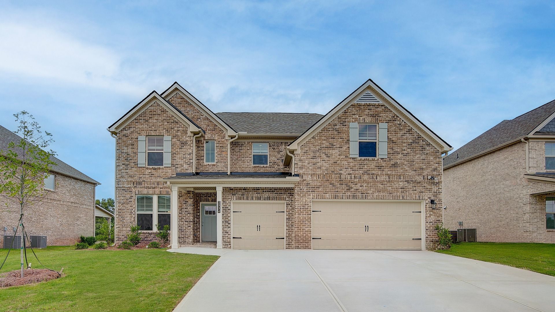 Four-sided brick exterior two-story home with three-car front-entry garage at the Clarity at Adagio in Dacula, GA.