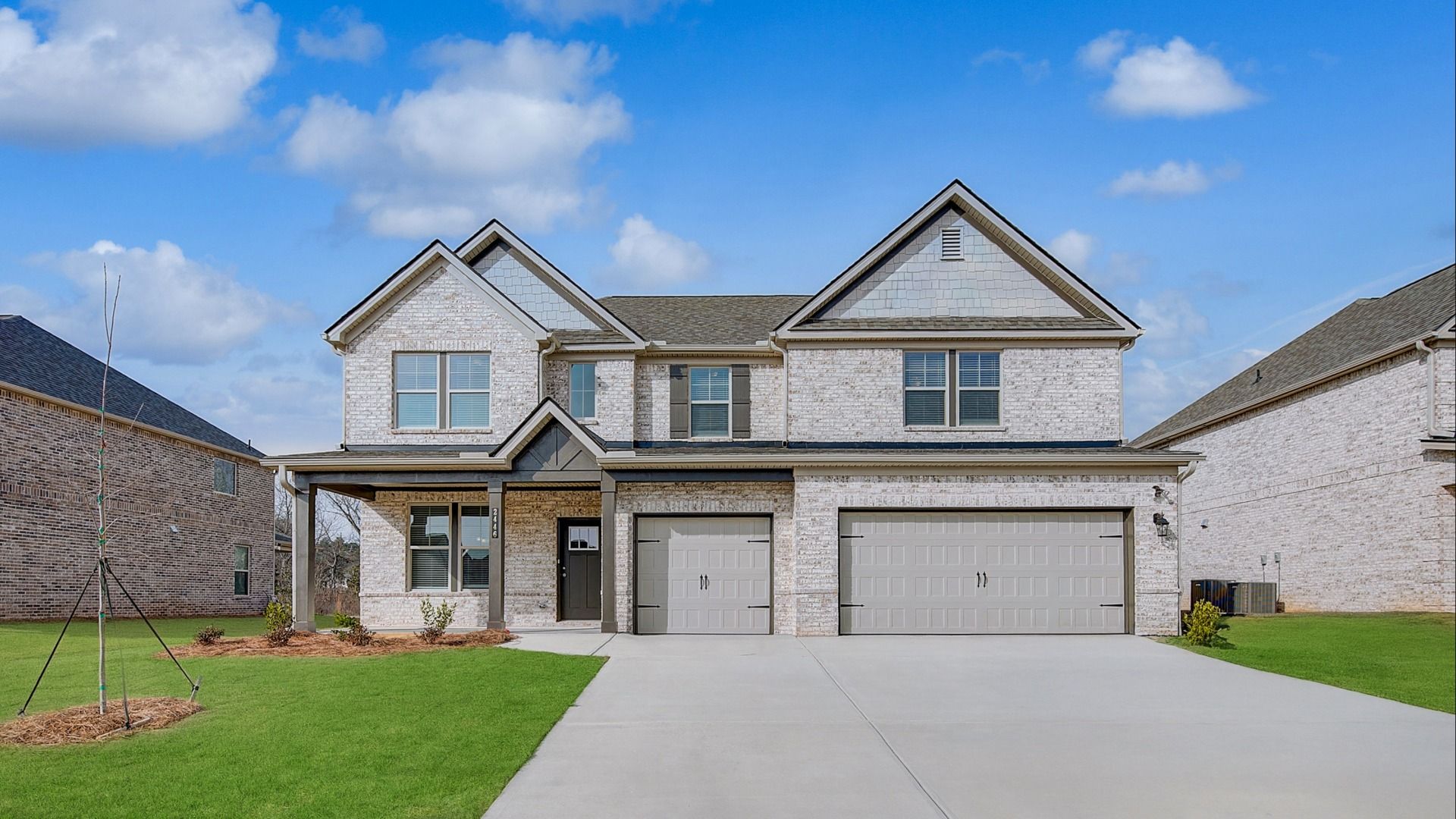 Two-story Clarity home featuring four-sided brick exterior with three-car front-entry garage at Adagio in Dacula, GA.