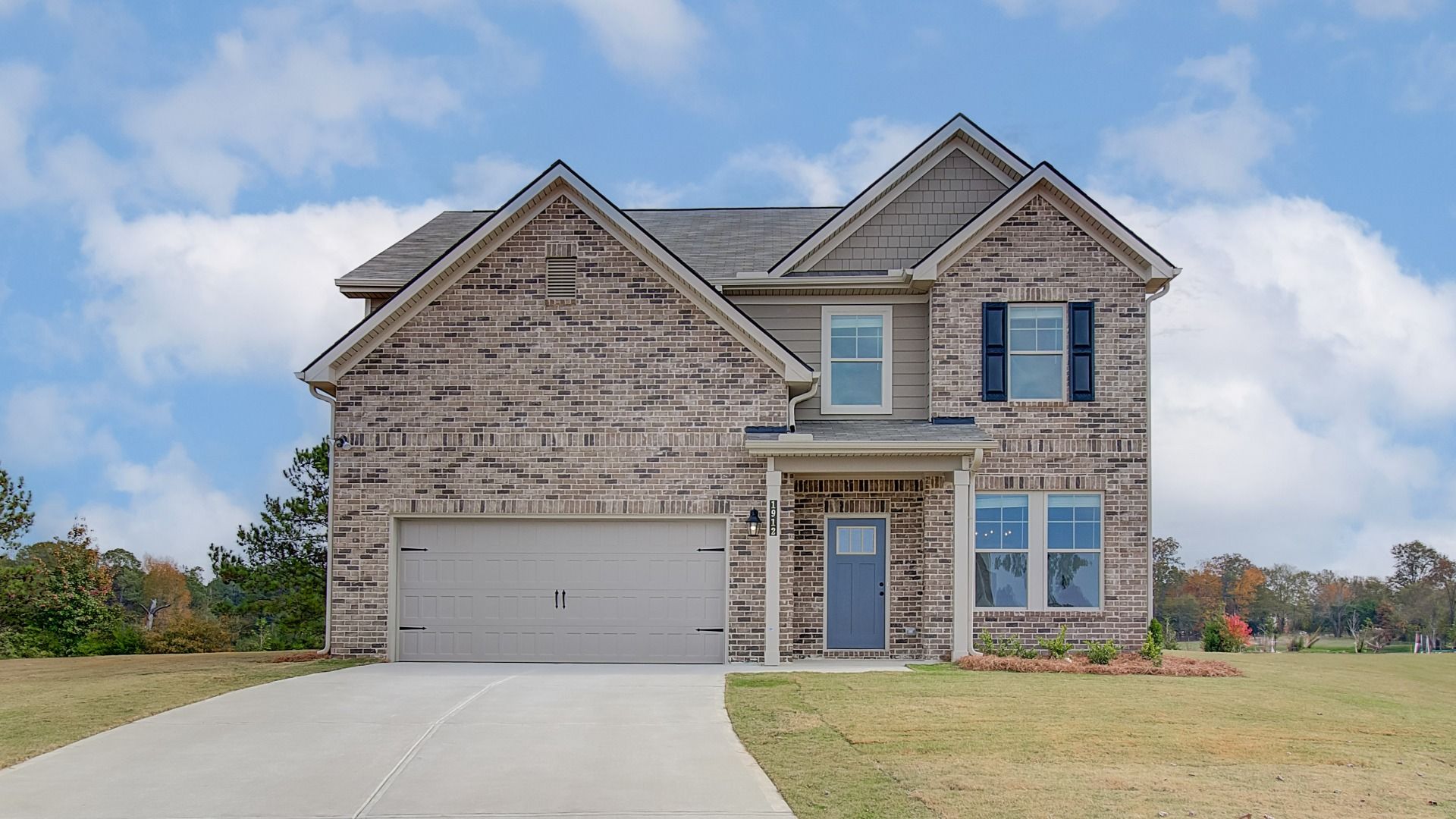 Oakmont single-family two-story home with brick exterior and two-car front-entry garage at Berkeley Lakes in Locust Grove, GA