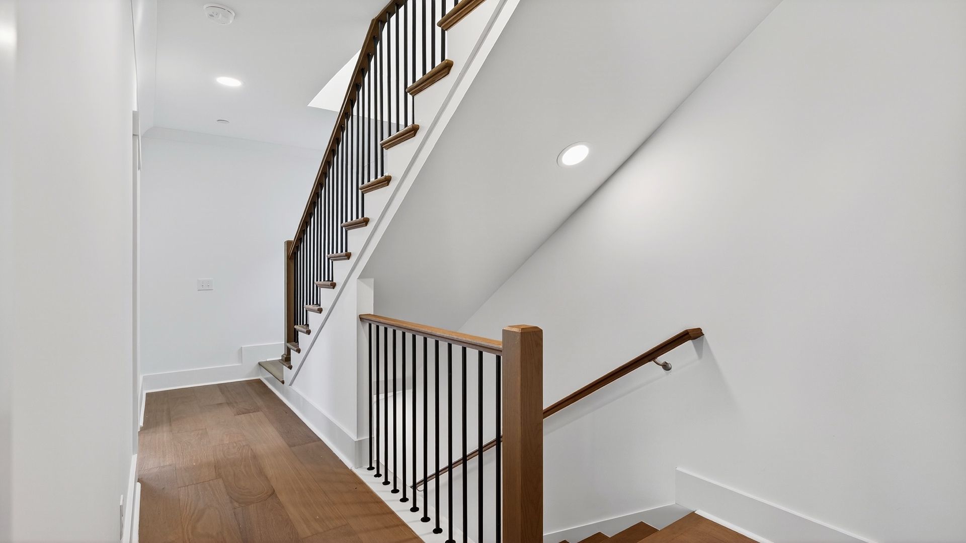 Interior hallway in the Seabrook home featuring hardwood flooring and a stylish staircase.