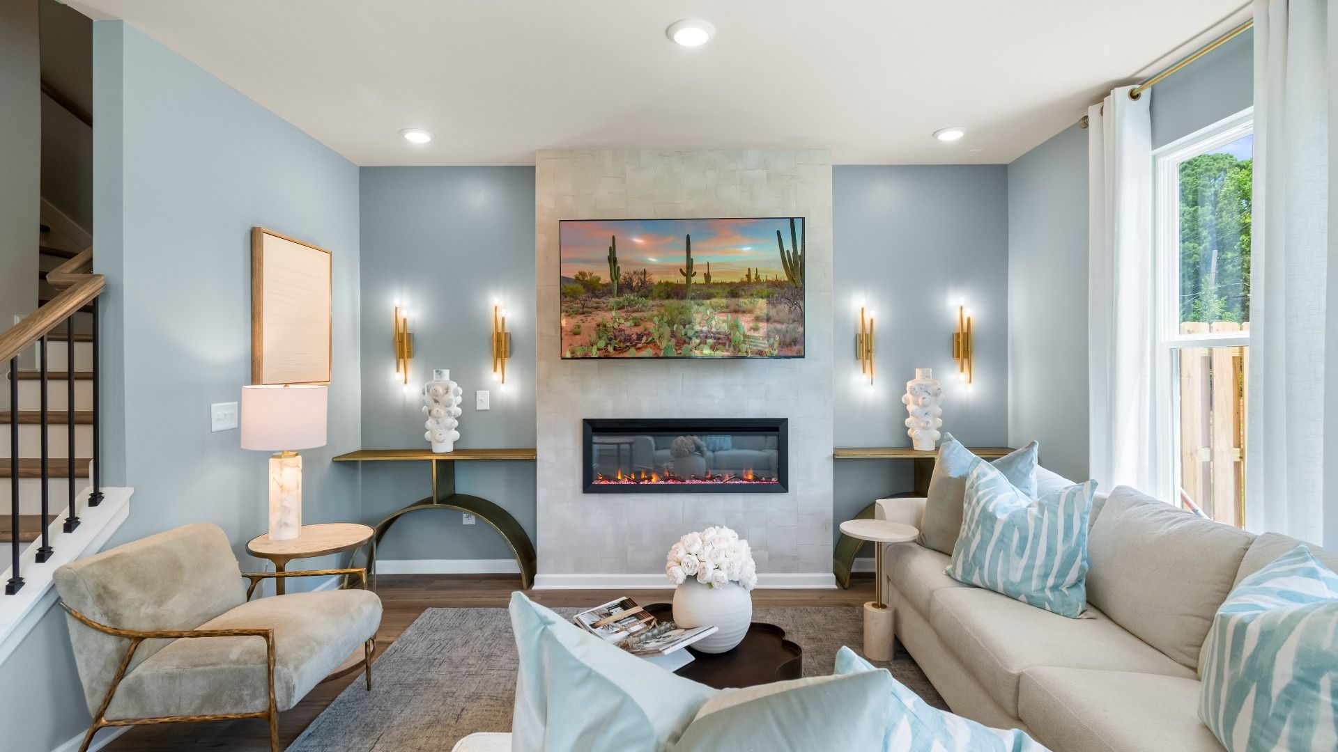 Bright blue family room with beige sectional and electric fireplace in townhome by DRB Homes in Conyers, GA
