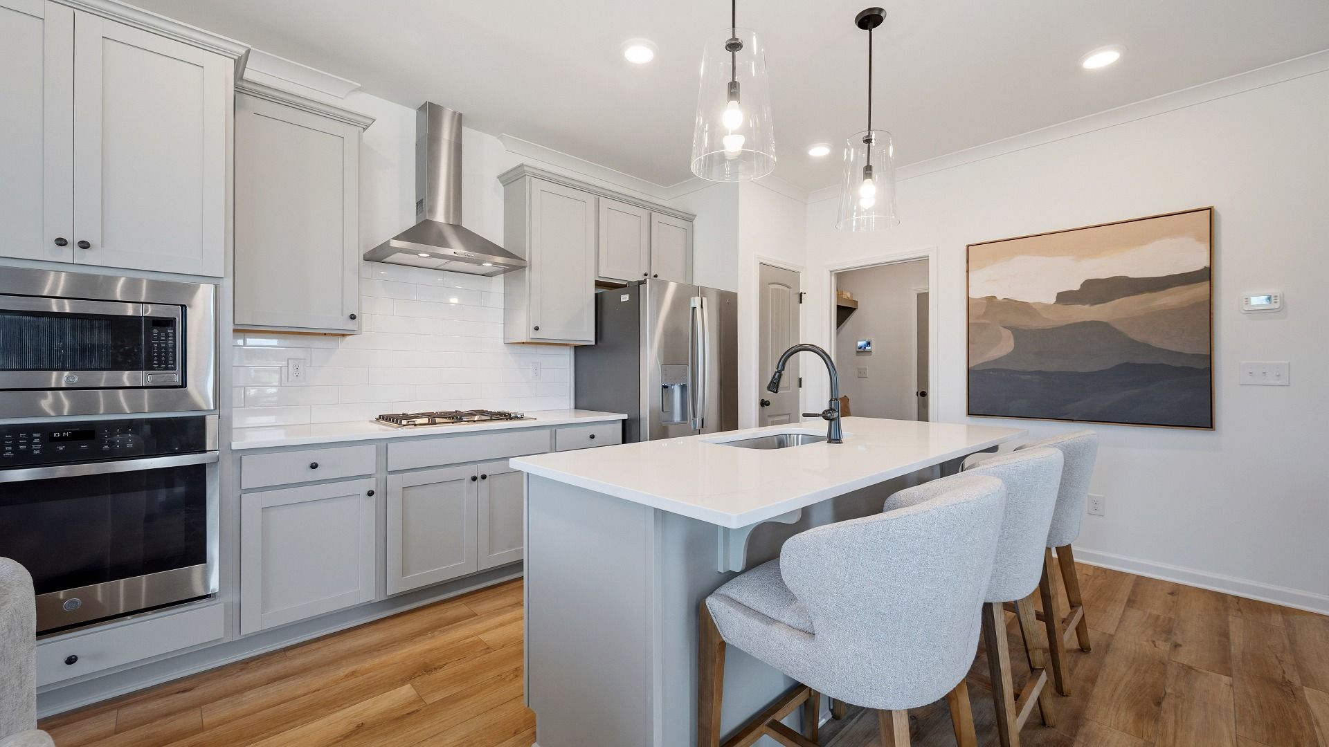 Modern kitchen with stacked microwave and oven, quartz countertops, and sleek cabinetry in townhome in Loganville, GA.