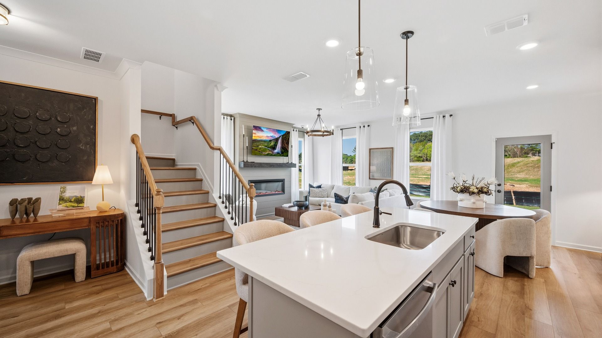 Bright open kitchen flowing into family room with island and natural light in Langley Overlook townhome in Loganville, GA.