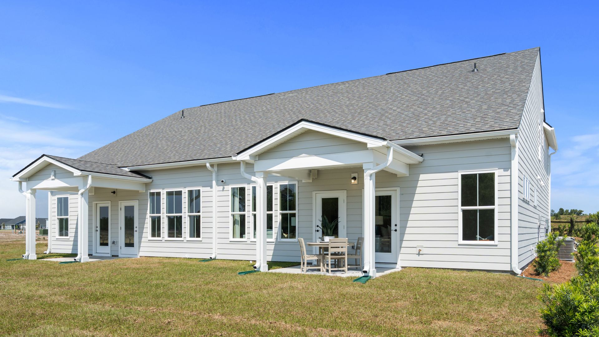 Rear exterior of the Summit home plan showcasing covered outdoor living and villa design.