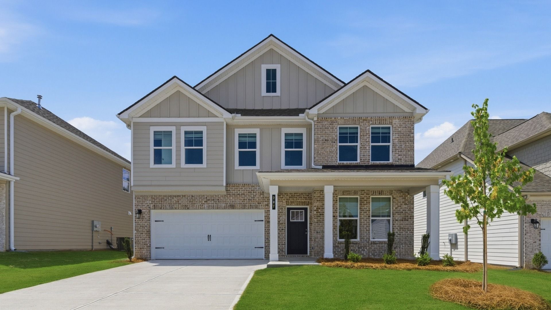 Beautiful two-story brick home in Abbotts Crossing, featuring manicured lawn, covered entry, and spacious two-car garage.