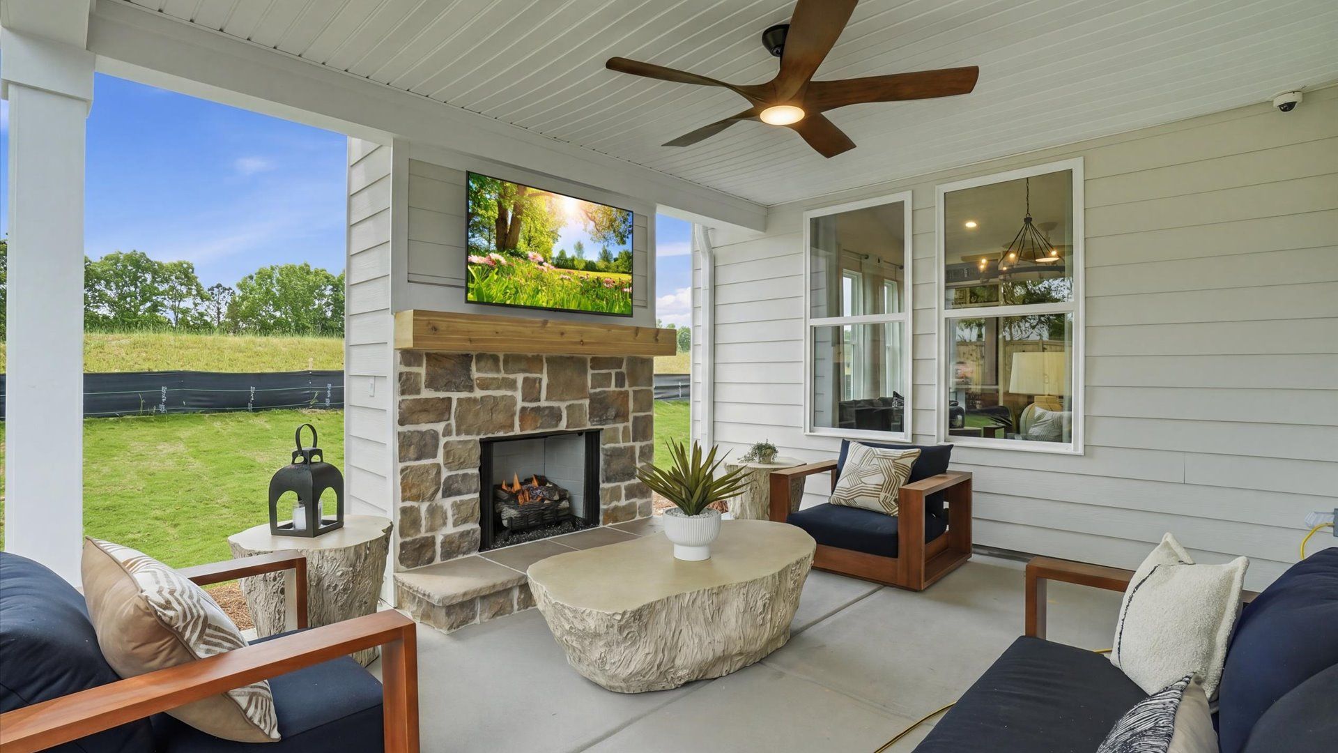 Covered outdoor porch with stone fireplace, TV, and spacious seating at Northcroft in Loganville, GA.
