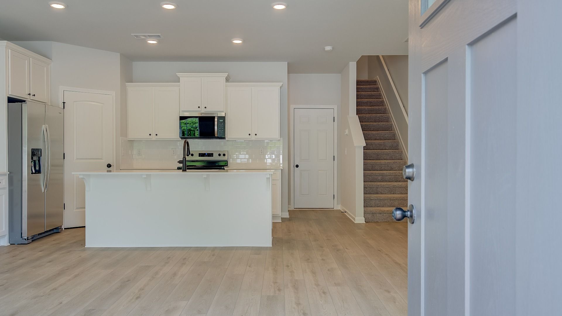 Mitchell entry with neutral front door and view into open-concept first floor at Avery Landing in McDonough, GA.