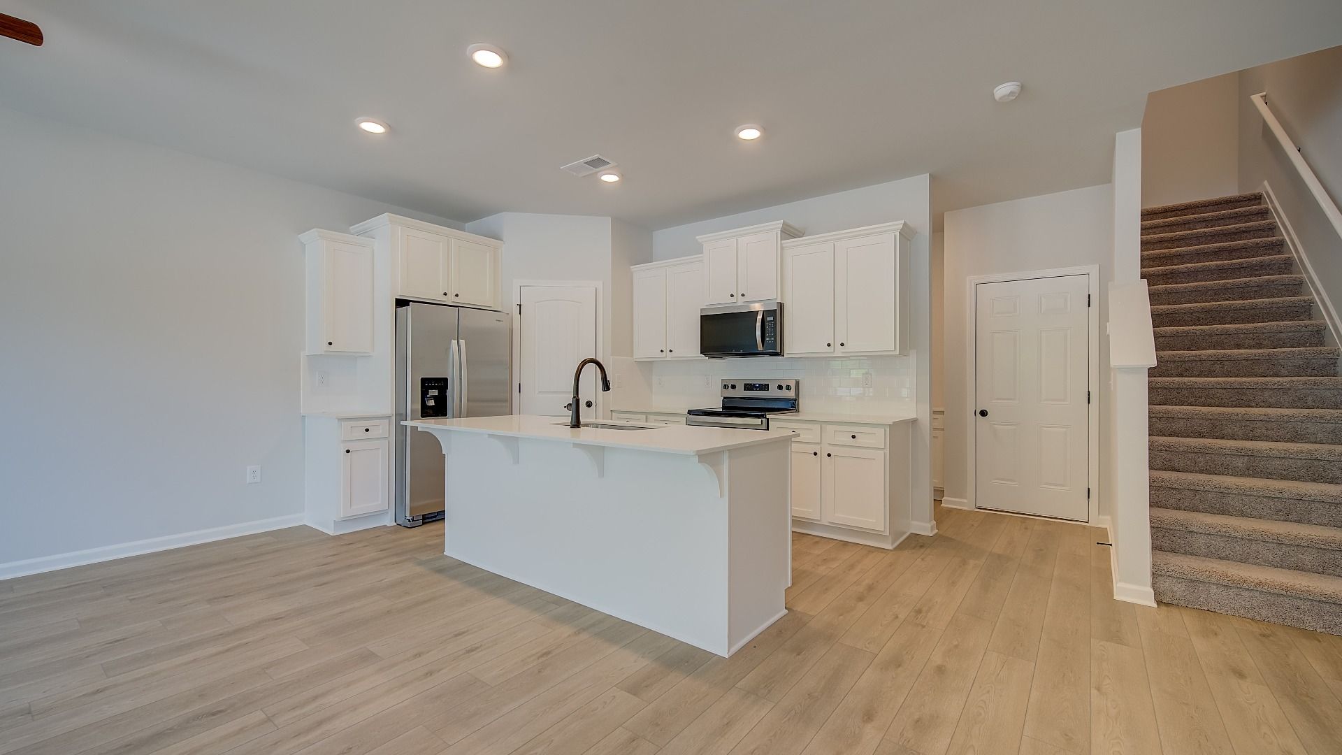 Mitchell modern open kitchen with white cabinetry, tile backsplash, and center island at Avery Landing.