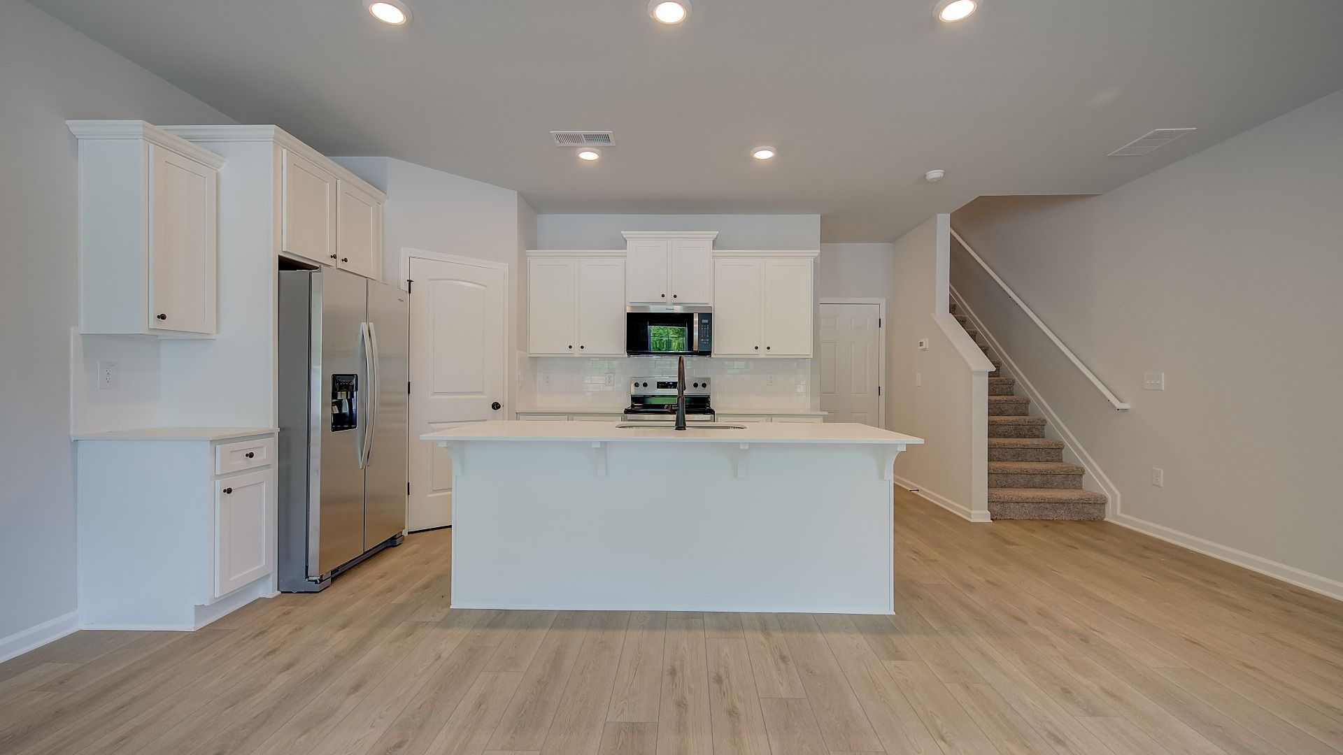 Bright open kitchen with white modern finishes, center island, and LVP flooring in the Mitchell at Avery Landing.