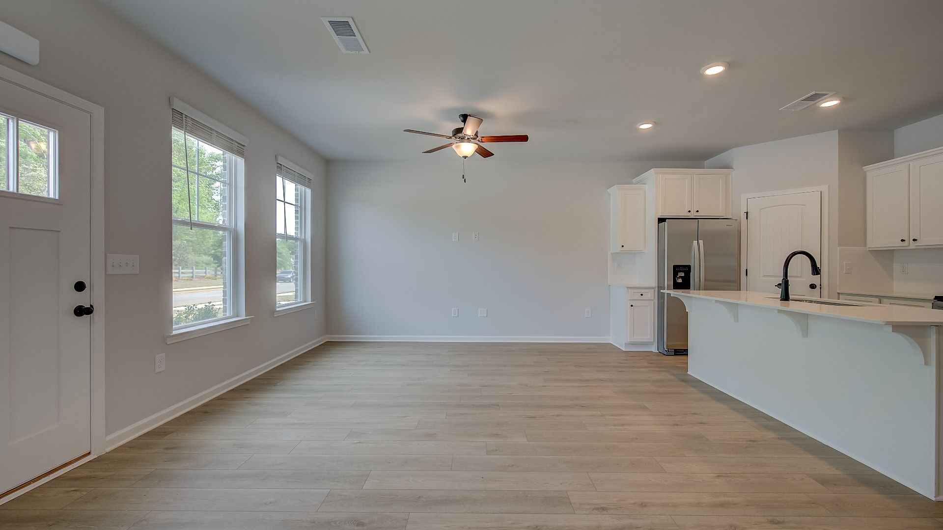 Open-concept family room with overhead fan, natural light and LVP flooring in the Mitchell at Adagio.