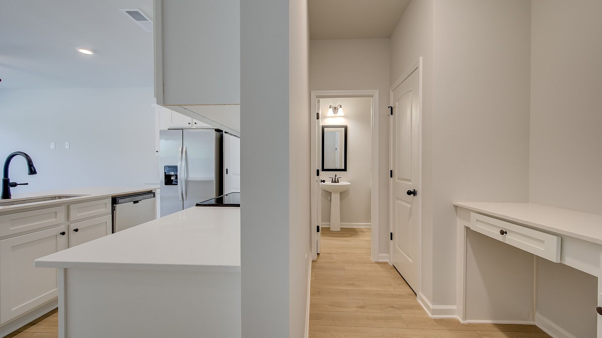 Open hallway with LVP flooring leading to kitchen and powder room in the Mitchell at Avery Landing.