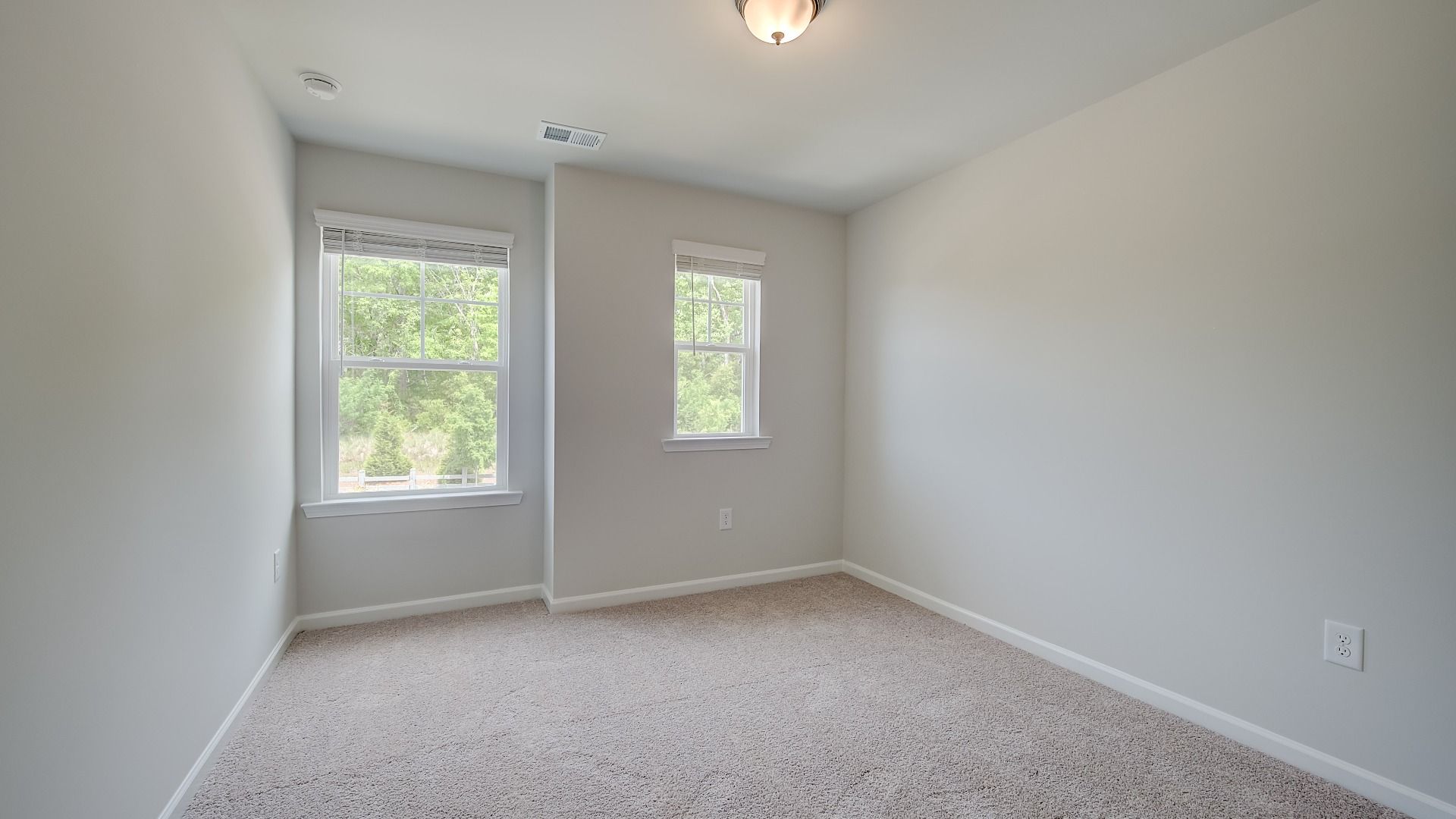Secondary bedroom with abundant natural light and carpet flooring in the Mitchell new construction townhome.