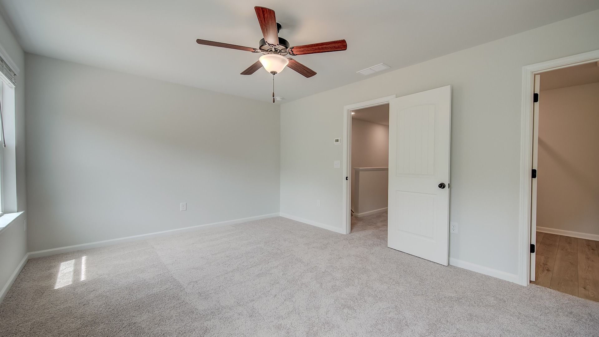 Spacious primary suite with natural light, carpet flooring, and overhead fan light in the Mitchell at Avery Landing.