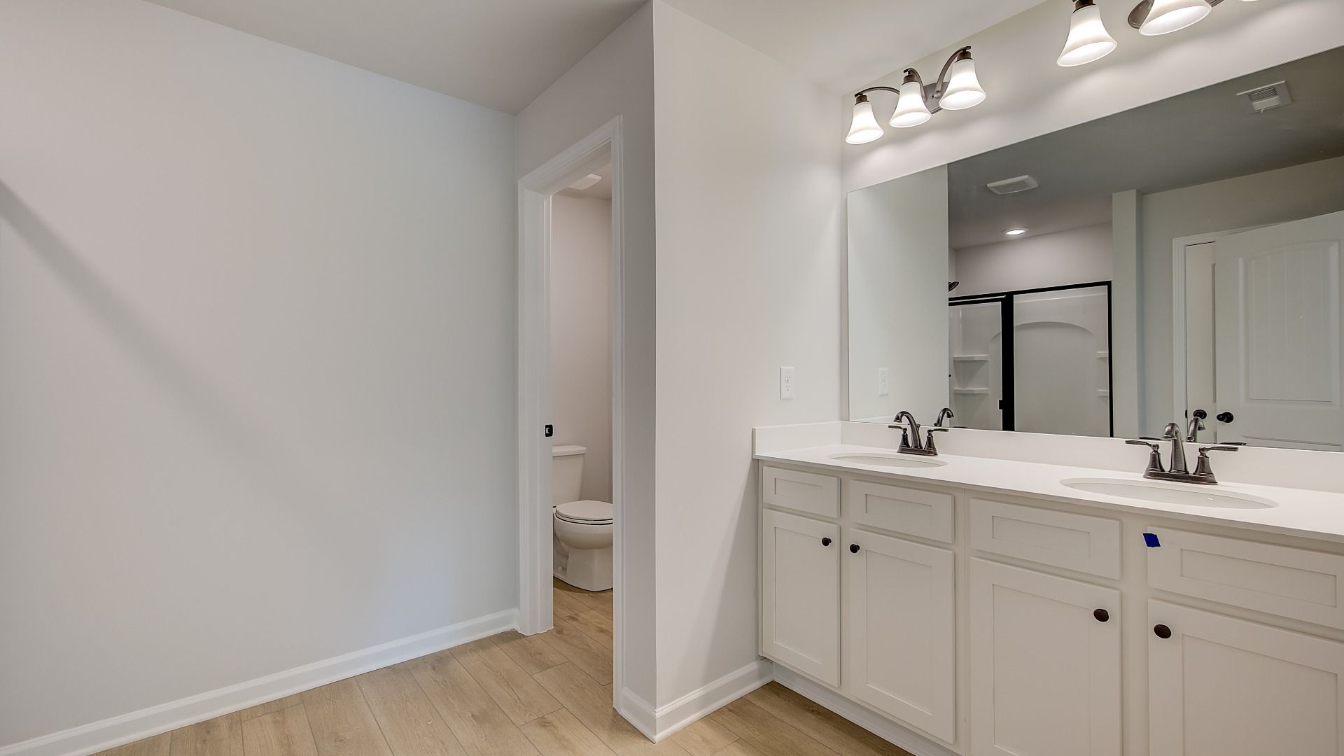 Primary bath with dual vanities, vanity lighting, and clean white finishes in the Mitchell at Avery Landing.