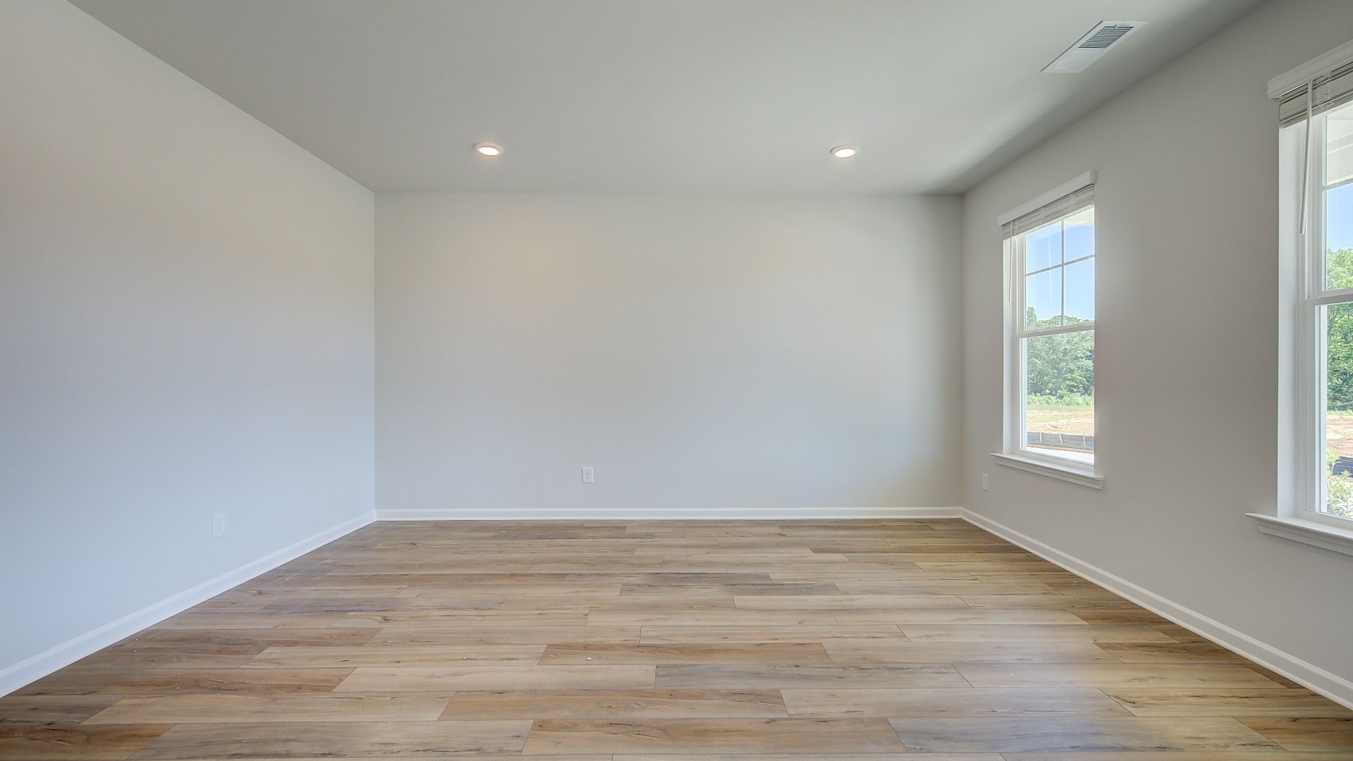 Bright living room with LVP flooring and large windows in the Clarity at Brighton in Locust Grove, GA.