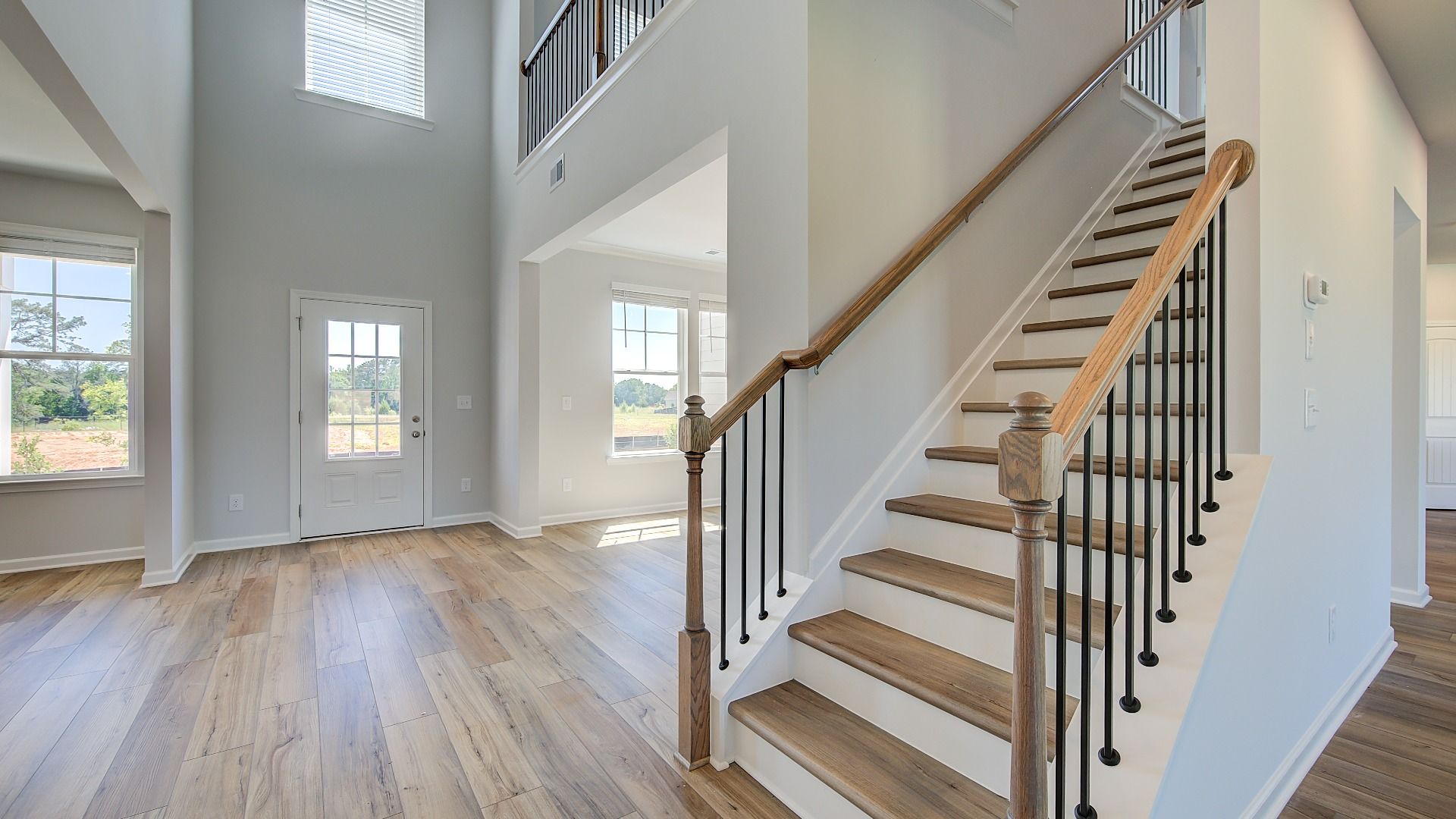 Clarity open foyer with staircase featuring open railing and LVP flooring at Brighton in Locust Grove, GA.