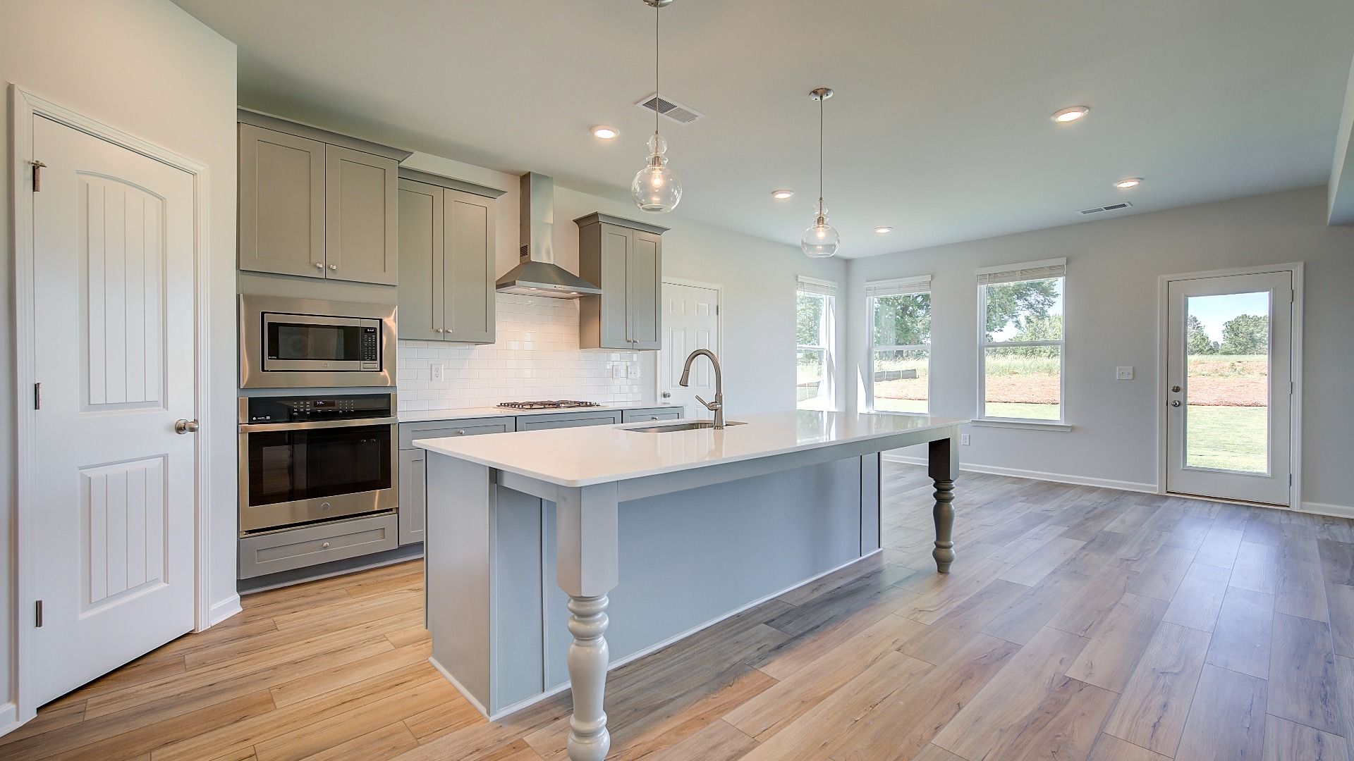 Open kitchen with large island, corner pantry, and stainless steel appliances in the Clarity at Brighton in Locust Grove, GA.