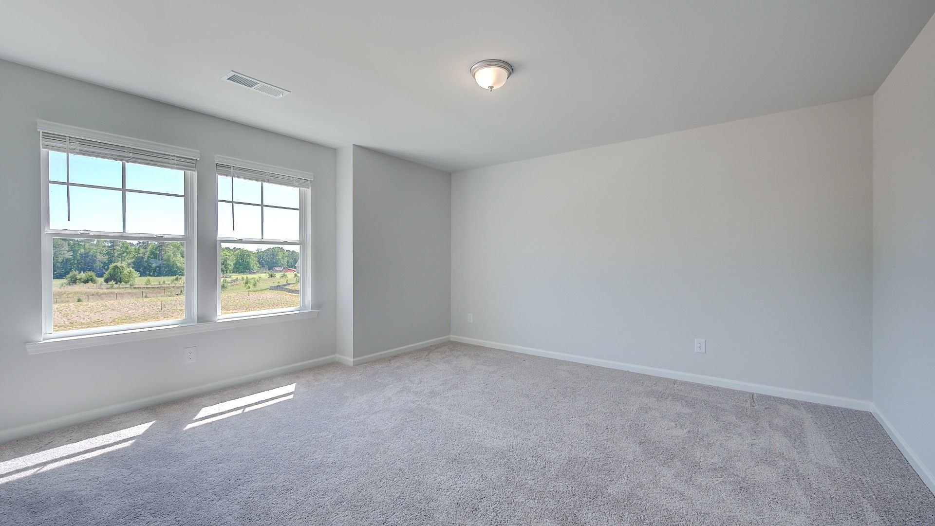 Spacious secondary bedroom with carpet flooring and natural light in the Clarity at Brighton in Locust Grove, GA.