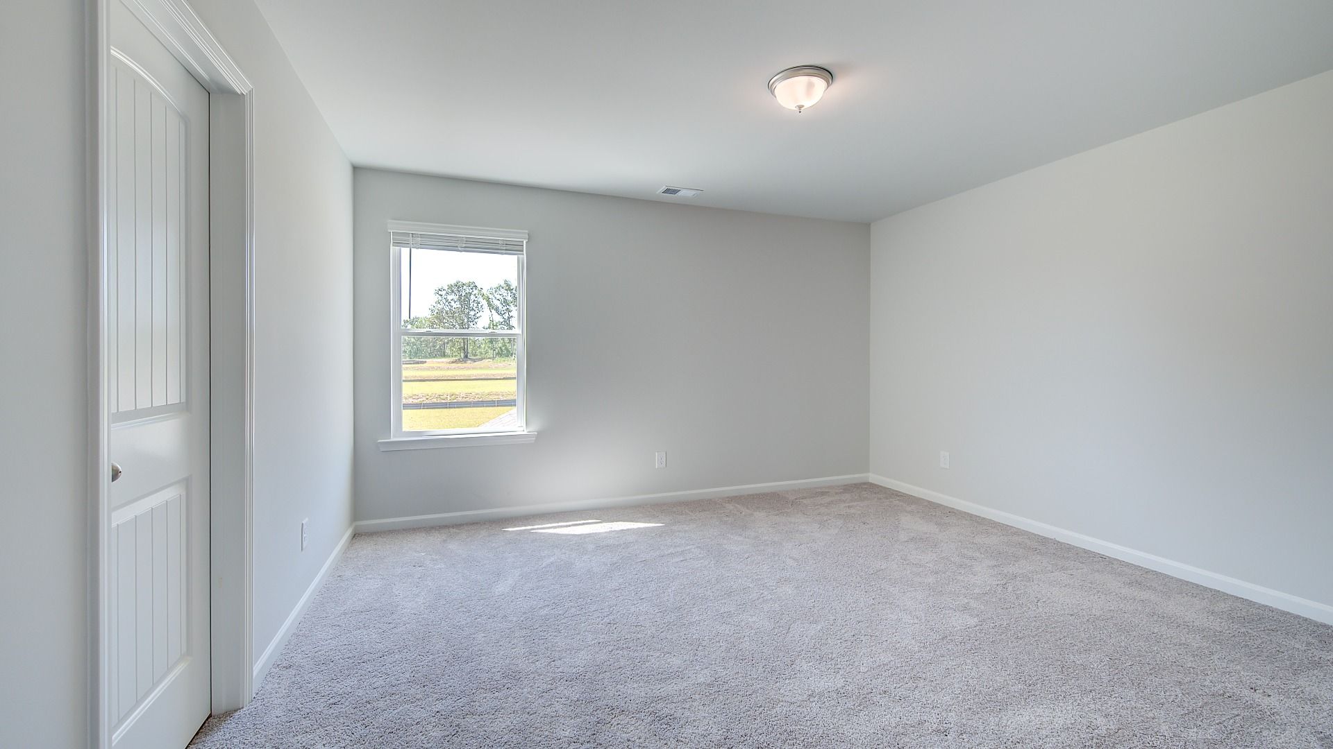 Carpeted secondary bedroom with neutral walls and natural light in the Clarity at Brighton in Locust Grove, GA.
