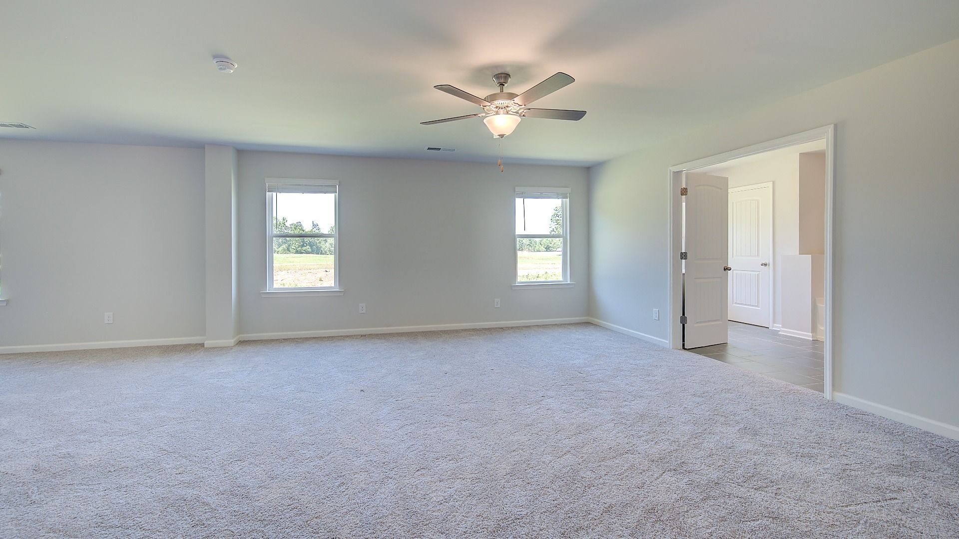 Expansive primary suite with carpet flooring, overhead fan light, and connecting bath in the Clarity at Brighton.