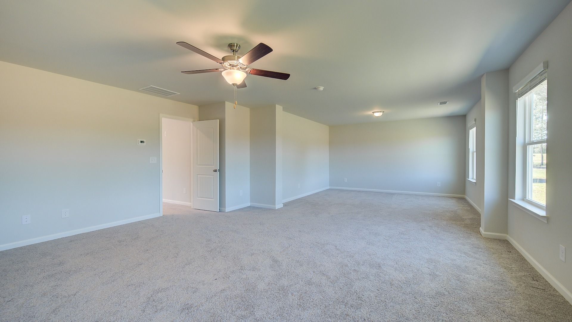 Spacious primary suite with sitting room, carpet flooring, and natural light in the Clarity at Brighton in Locust Grove, GA.
