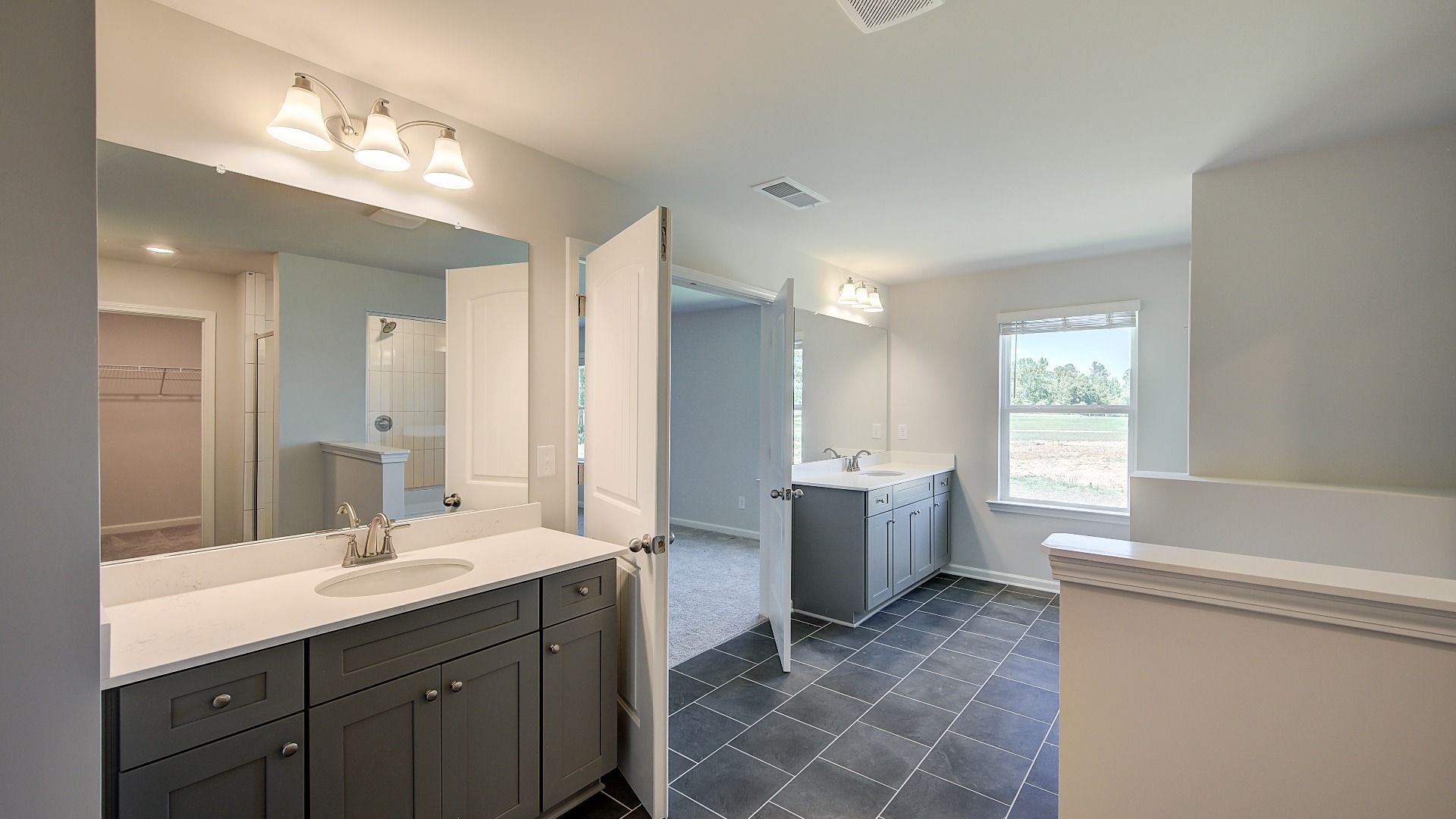 Luxury primary bath with dual vanities, freestanding tub, and neutral modern finishes in the Clarity at Brighton.