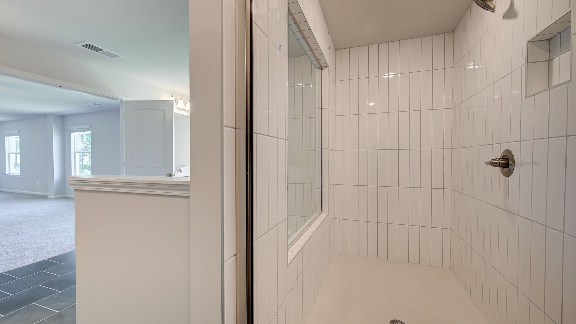 Primary bath featuring oversized walk-in shower with bright tile wall in the Clarity at Brighton in Locust Grove, GA.