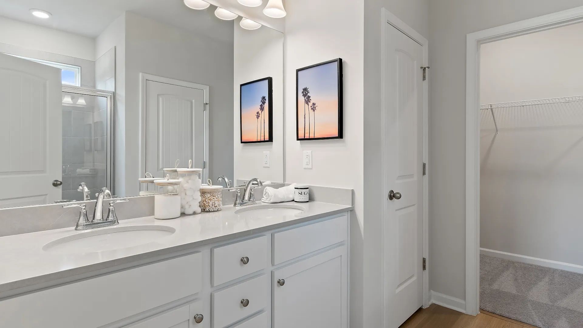 Private bath with double sinks, walk-in closet with shelving, and tiled shower at Westminster in Covington, GA.