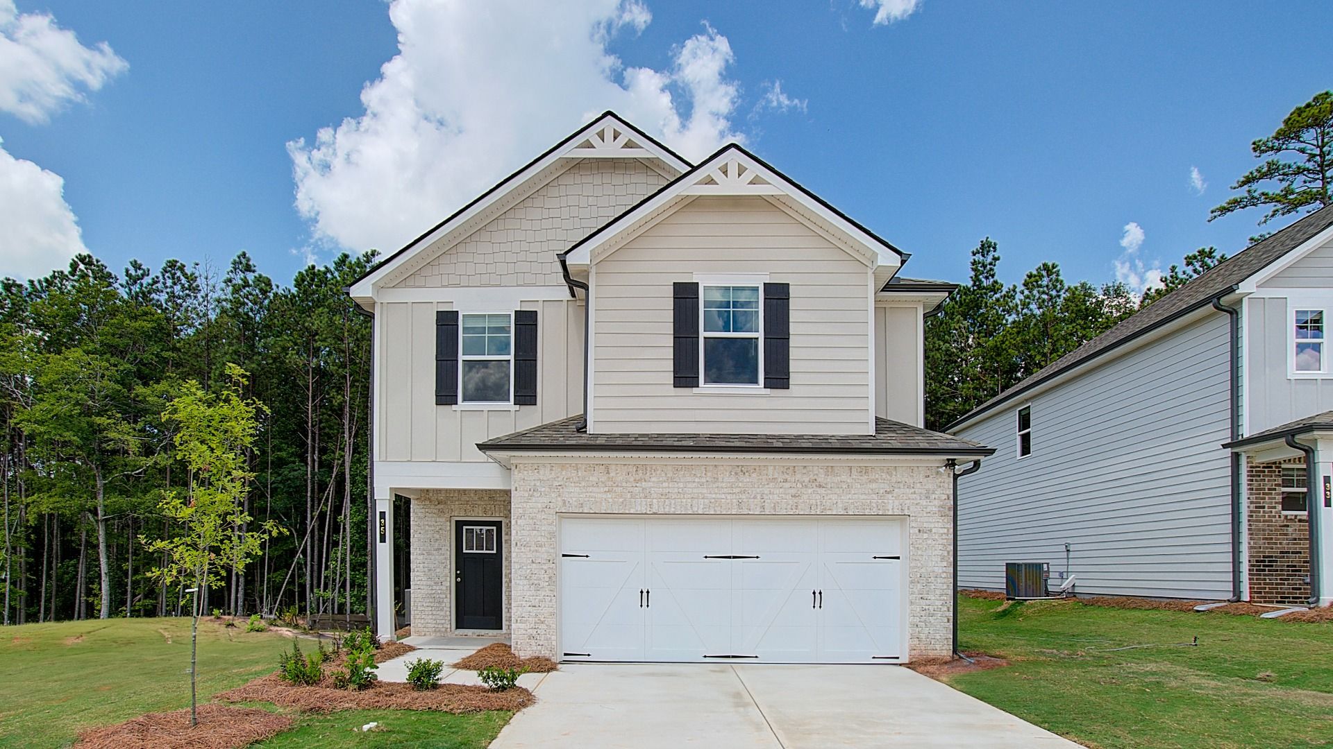Light-colored reagan exterior with brick accents and attached two-car garage at Enclave at Evergreen in Fairburn, GA.