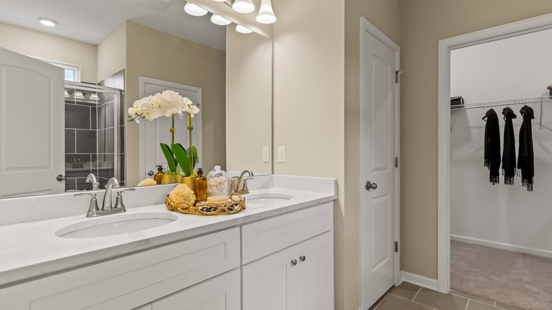 Private primary bath featuring double vanity and shower with modern tile wall detail at Enclave at Evergreen in Fairburn, GA.