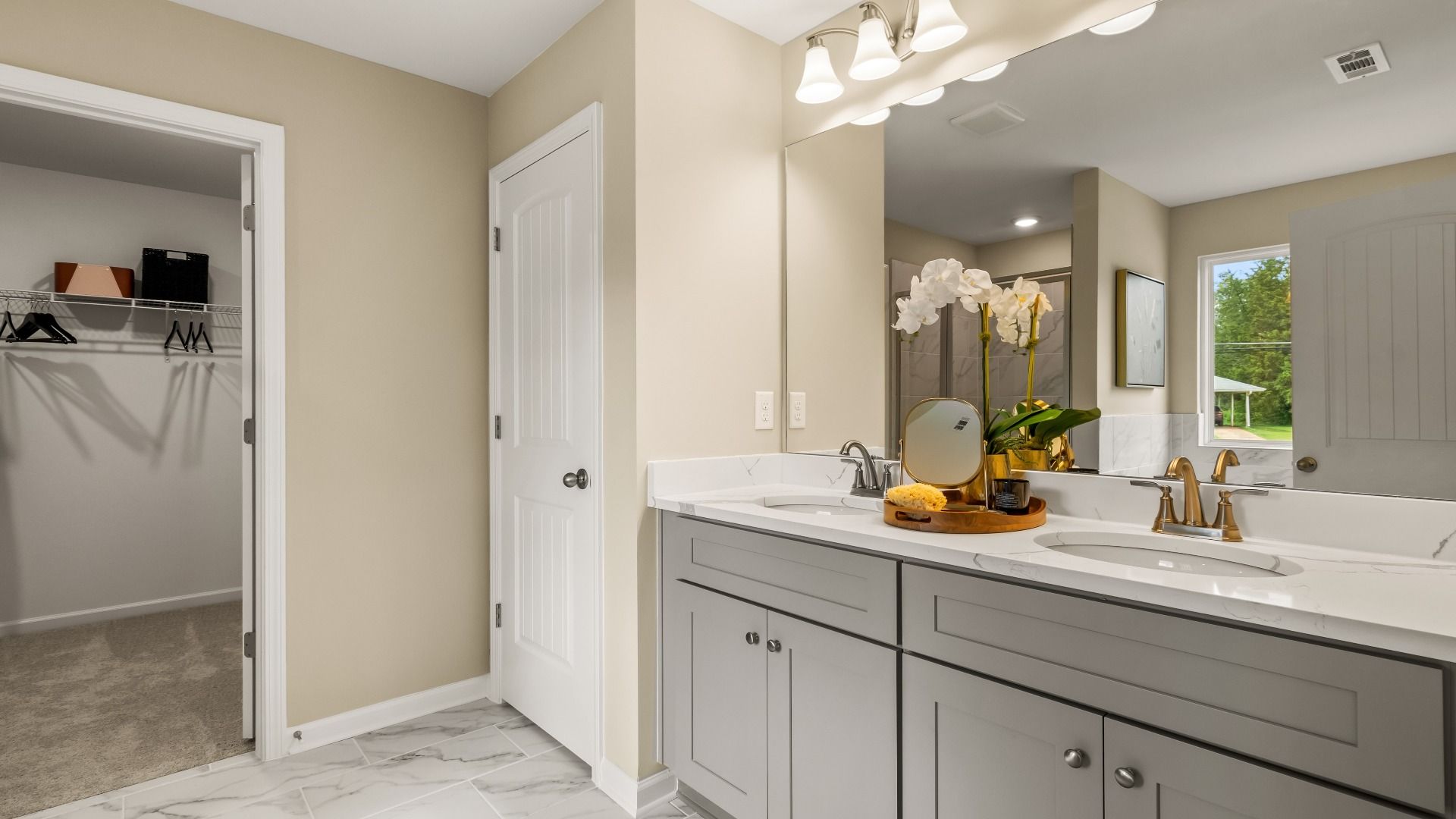Primary bath with neutral modern finishes featuring double vanity and walk-in closet at Enclave at Evergreen in Fairburn, GA.