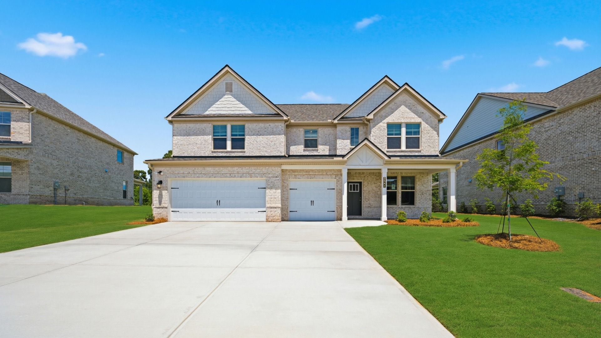 Two-story Clarity home with four-sided light brick exterior and three-car front-entry garage at Adagio in Dacula, GA.